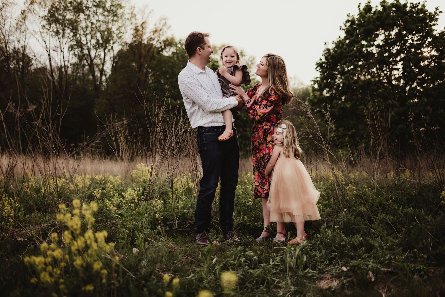A sweet family moment captured outdoors with floral dress and pale pink tulle dress against natural scenery.