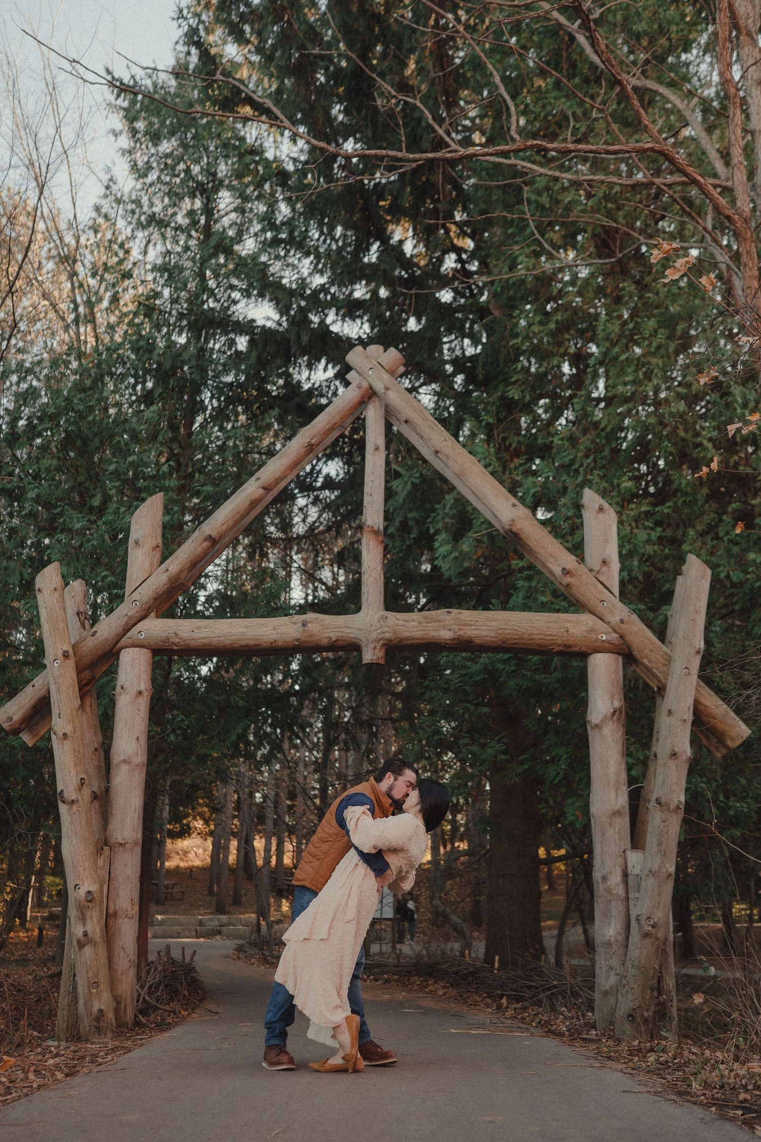 Rustic wooden archway made from tree branches creates a romantic woodland setting at sunset.