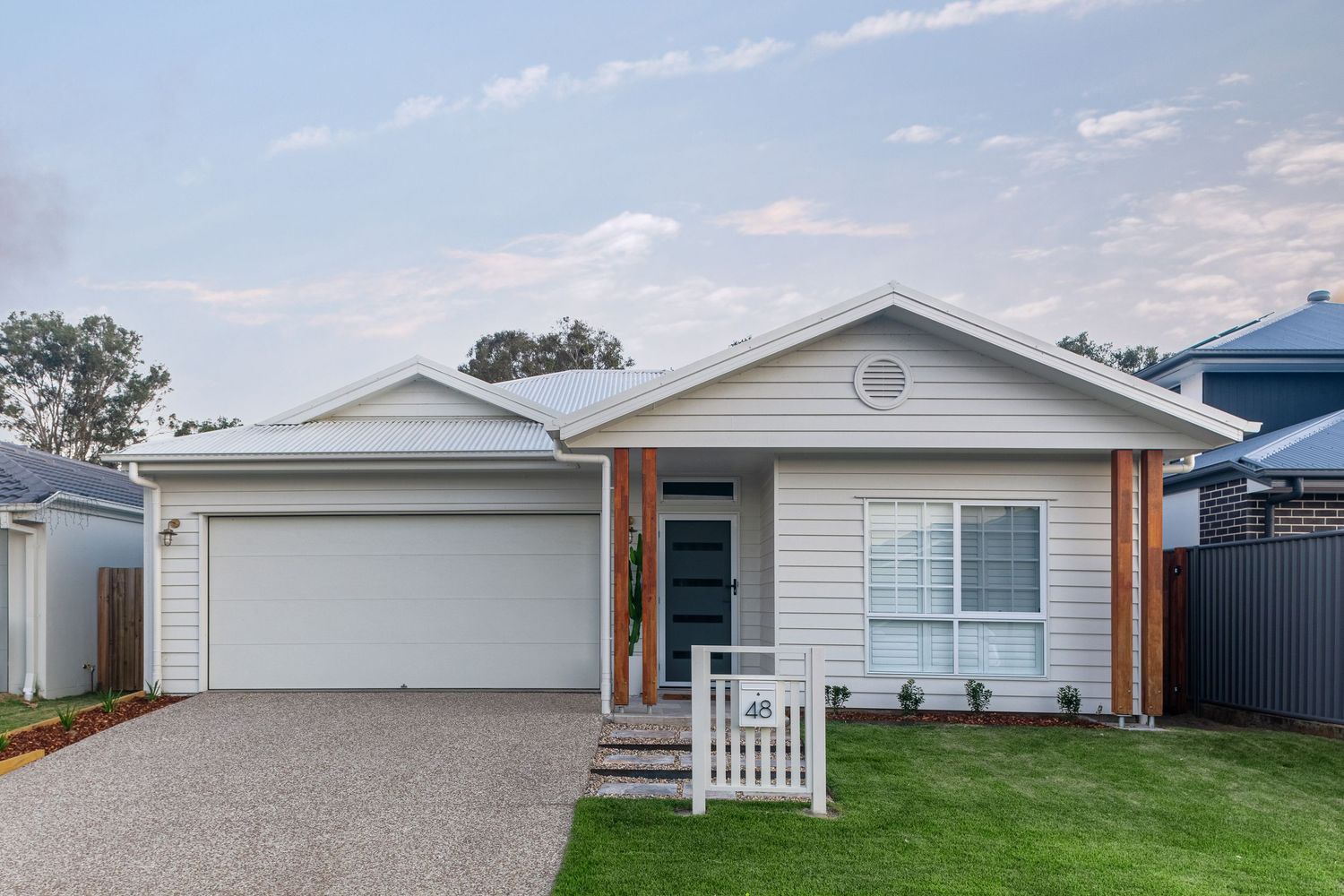 Sunshine Coast real estate photography: modern white weatherboard family home featuring timber accents, double garage, and a neat front lawn
