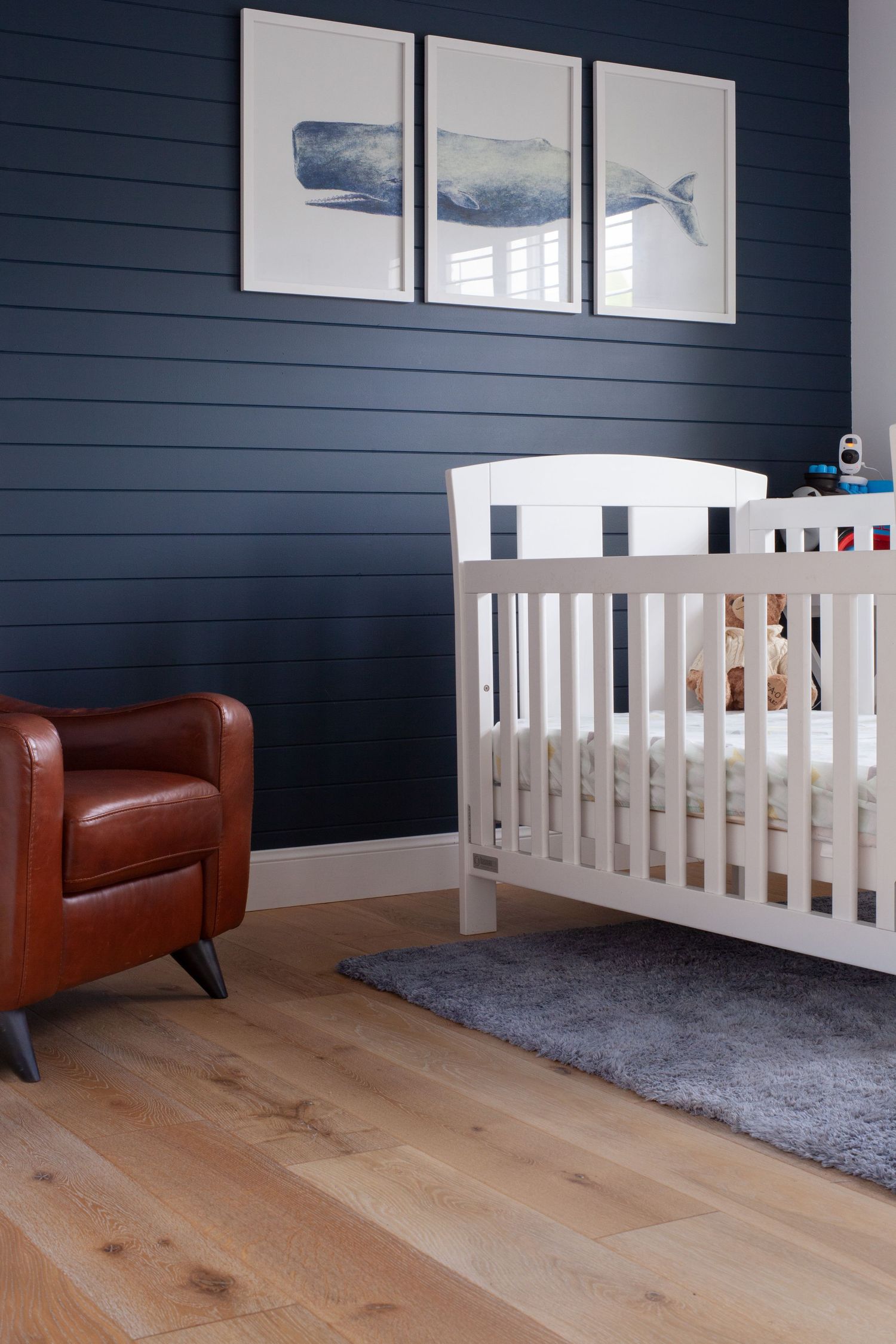 Sunshine Coast real estate photography: modern nursery featuring navy shiplap wall, white crib, and nautical whale artwork triptych
