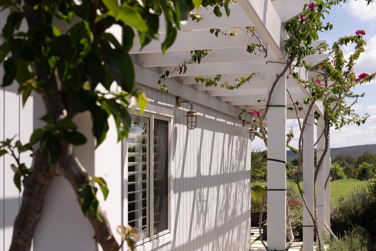 Sunshine Coast real estate photography: modern white weatherboard exterior with architectural pergola and climbing bougainvillea vines