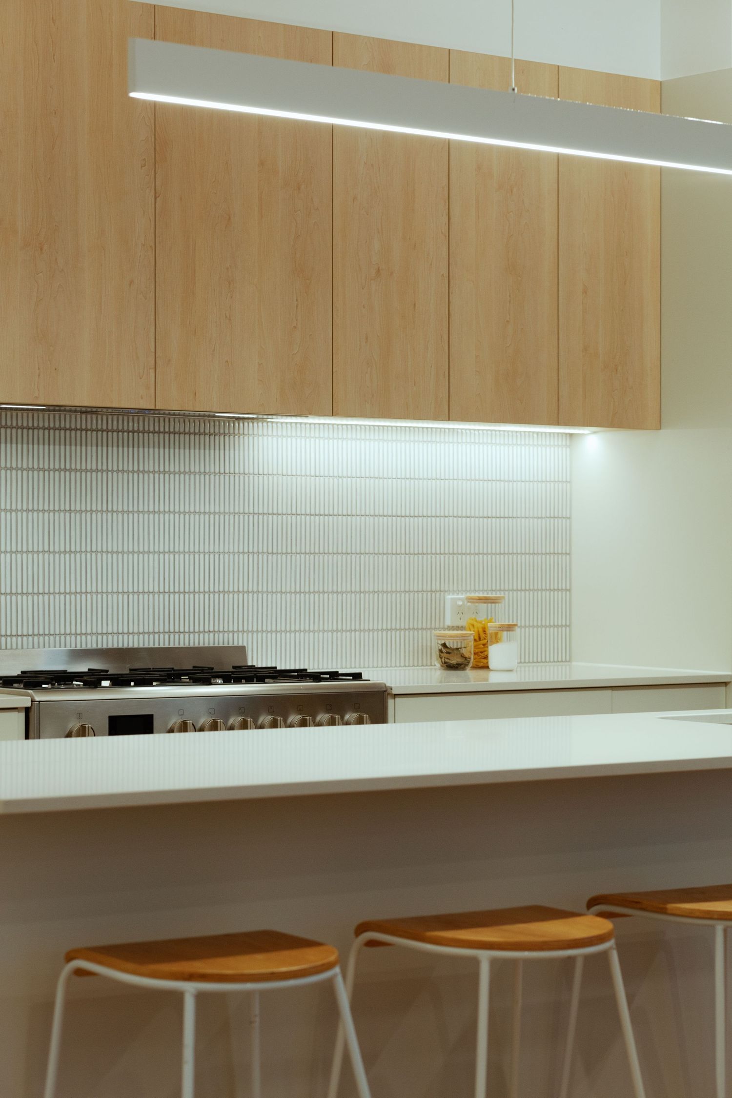 Sunshine Coast real estate photography: minimalist kitchen with light wood cabinetry, white vertical Japanese tiles, and modern LED lighting