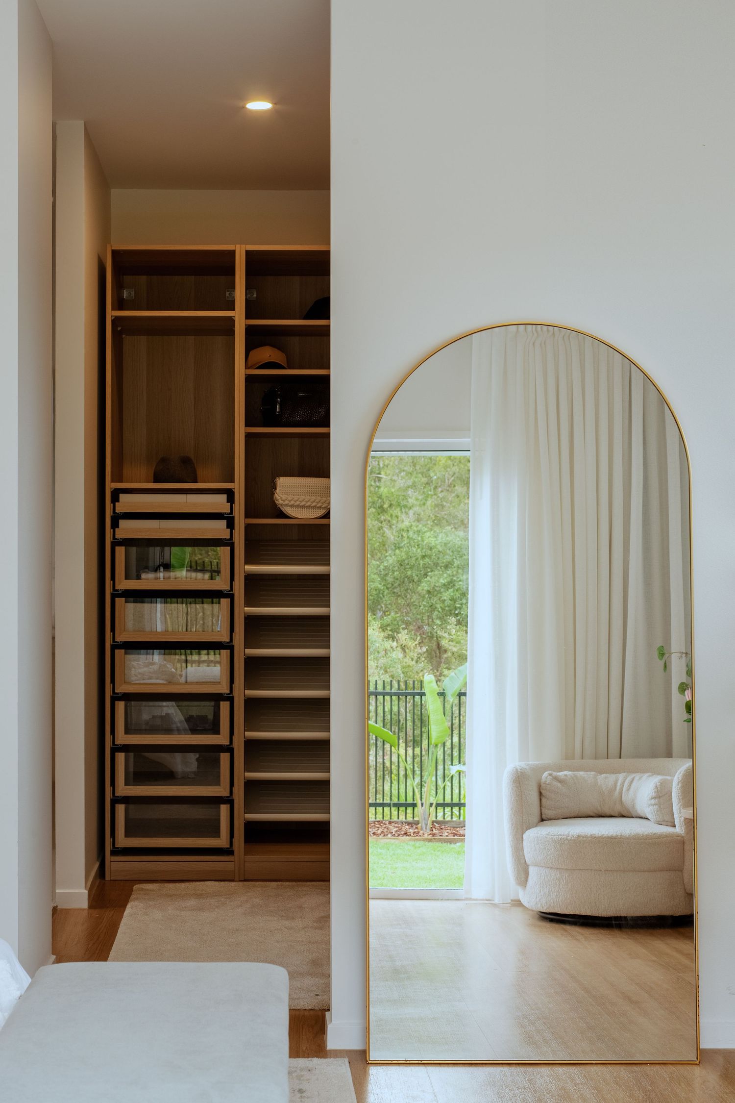 Sunshine Coast real estate photography: luxury master walk-in wardrobe and arched gold floor mirror reflecting a modern coastal bedroom