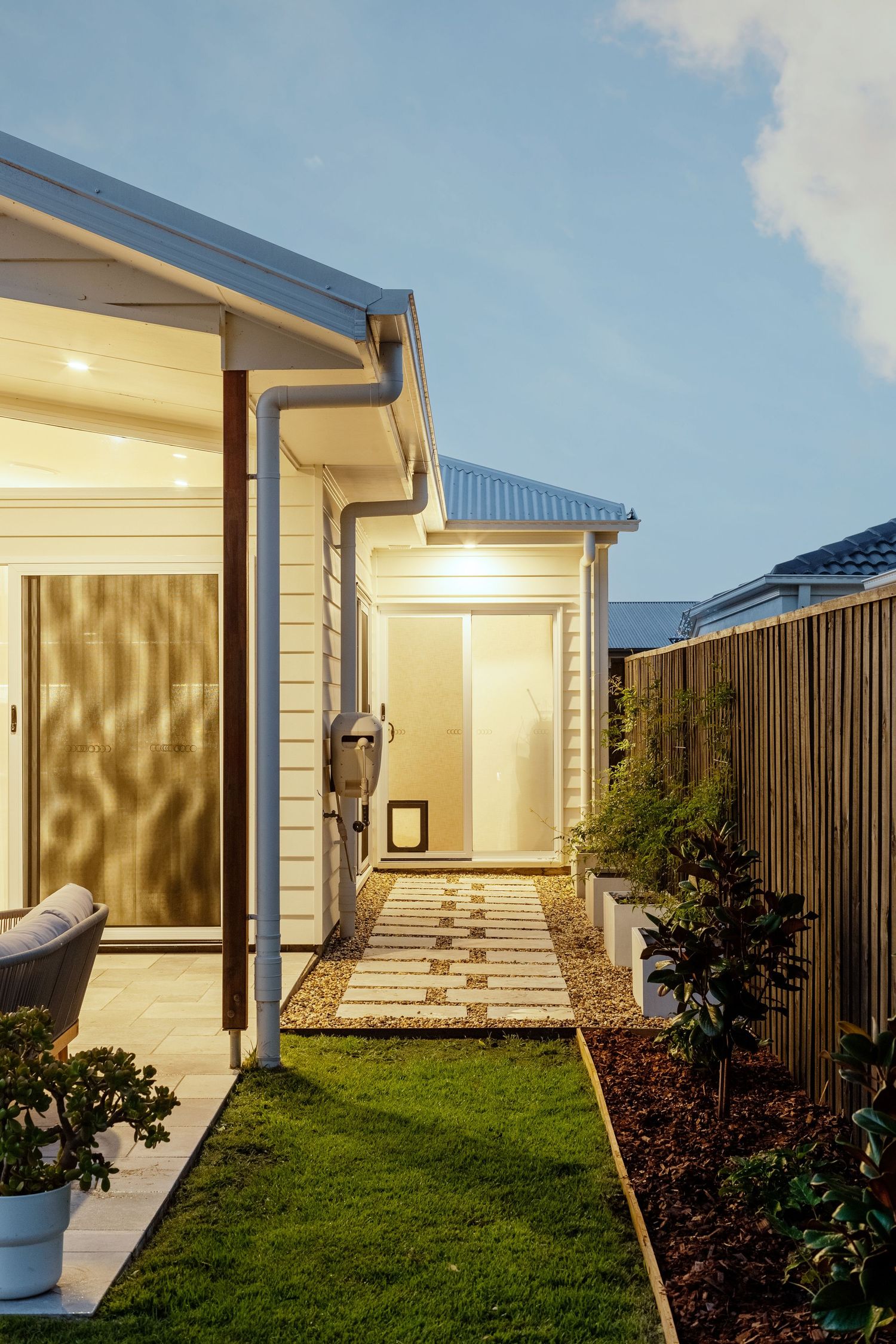 Sunshine Coast real estate photography: modern white weatherboard home exterior at twilight with stone paver path and manicured garden beds