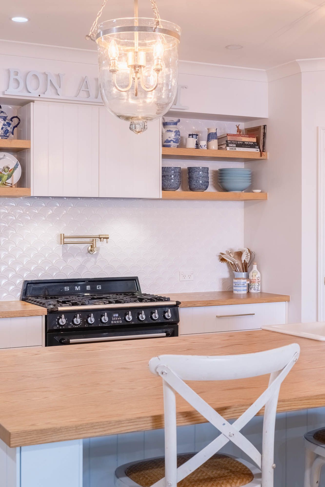 Sunshine Coast real estate photography: coastal Hamptons kitchen with Smeg stove, white fan tiles, timber counters, and open shelving
