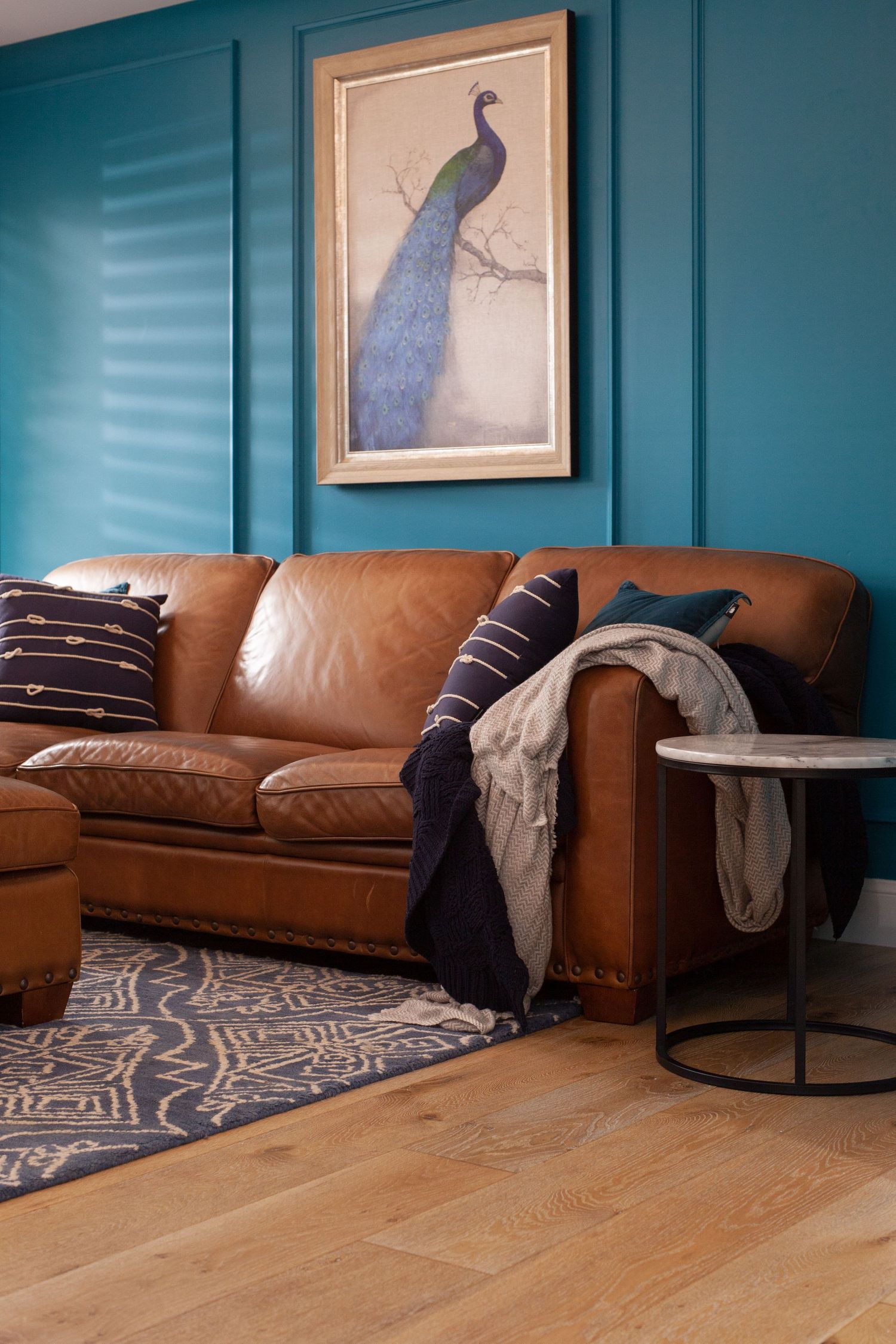 Sunshine Coast real estate photography: luxury living room with brown leather sofa, teal paneled wall, and elegant peacock artwork