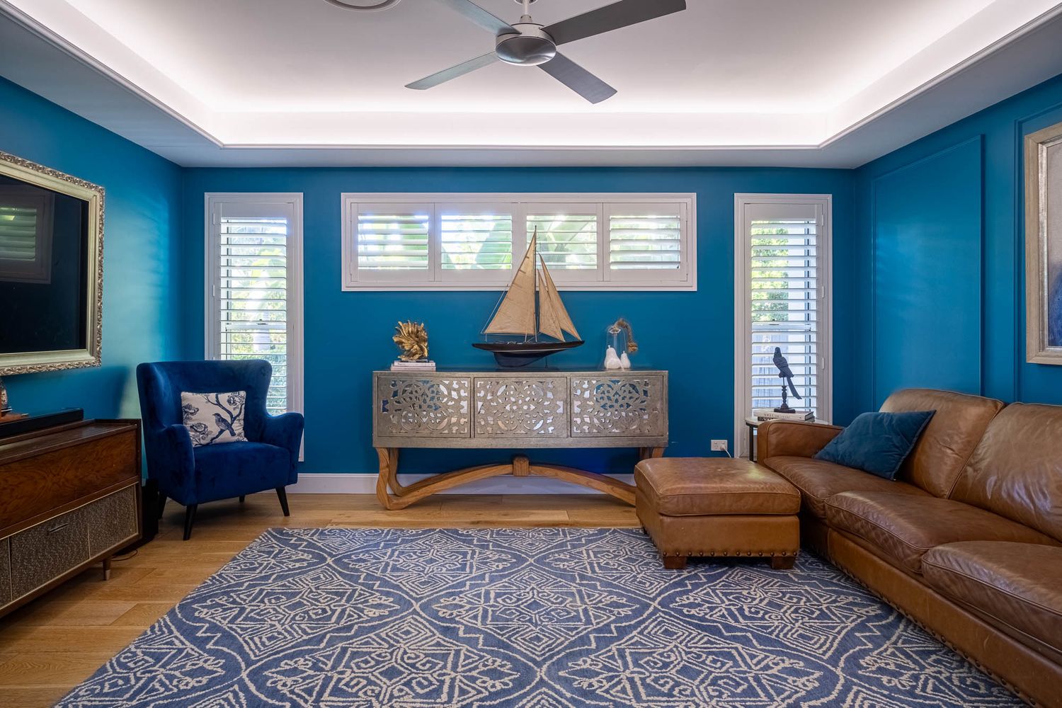 Sunshine Coast real estate photography: luxury teal living room with model sailboat, blue wingback chair, and leather sofa styling.
