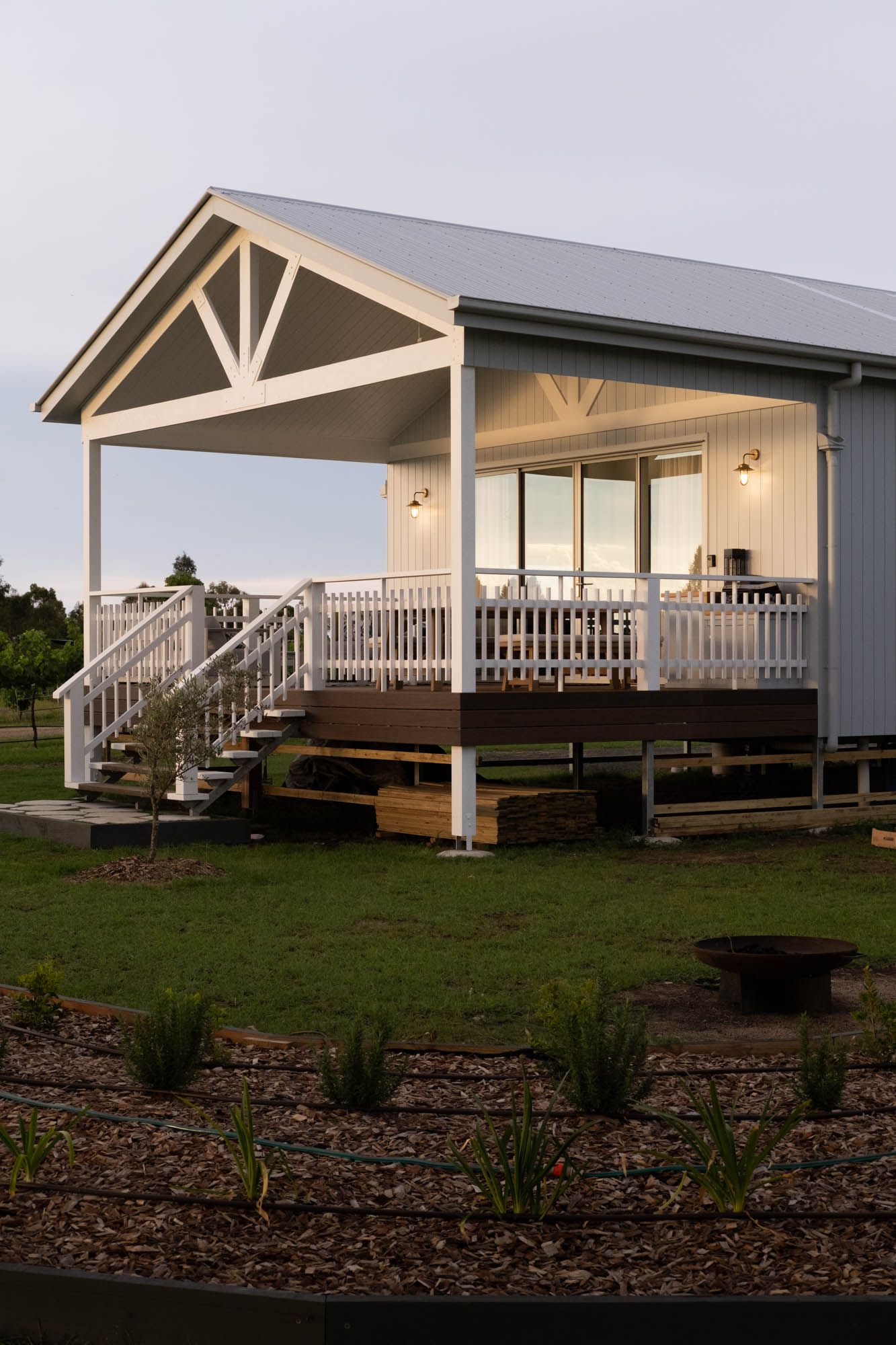 Sunshine Coast real estate photography: modern white weatherboard cabin exterior with a large architectural gabled porch at twilight