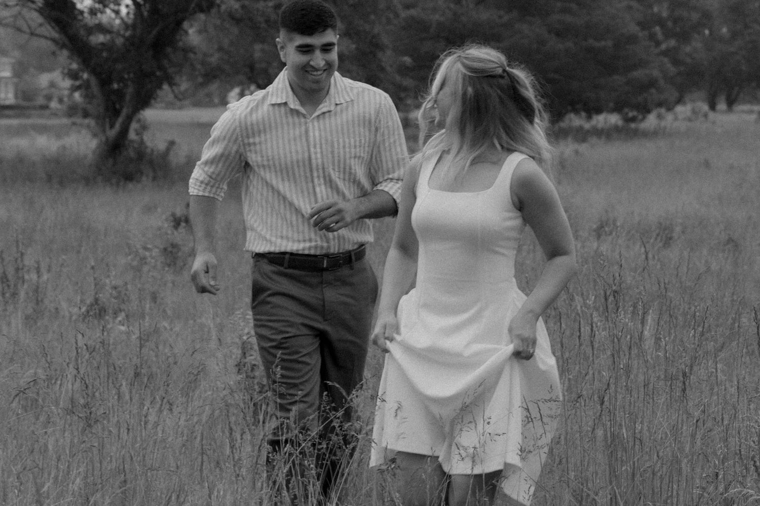 A romantic moment captured between two people walking through tall grass.