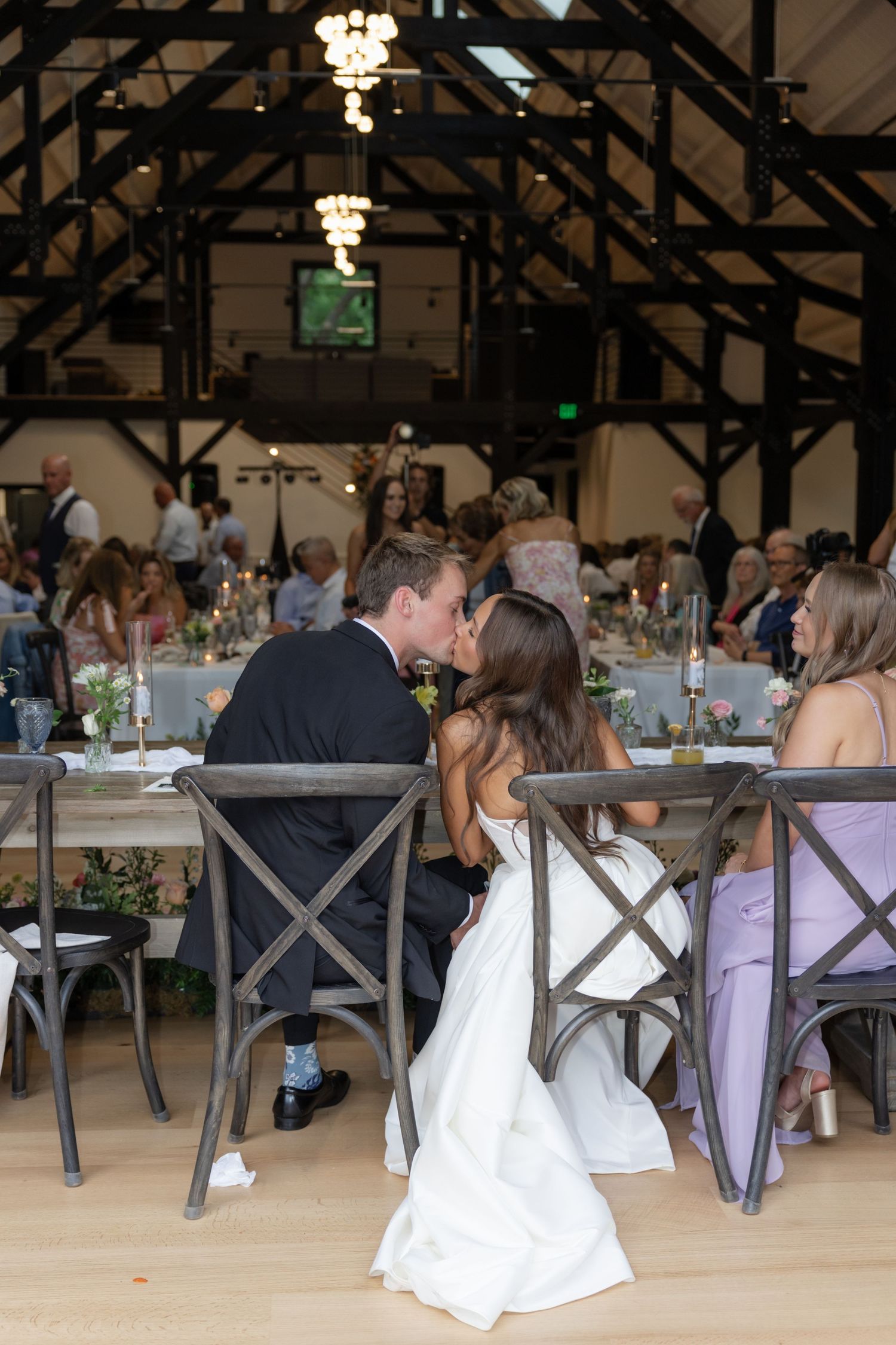 Reception hall set with rustic wooden chairs and purple accents for a wedding celebration.