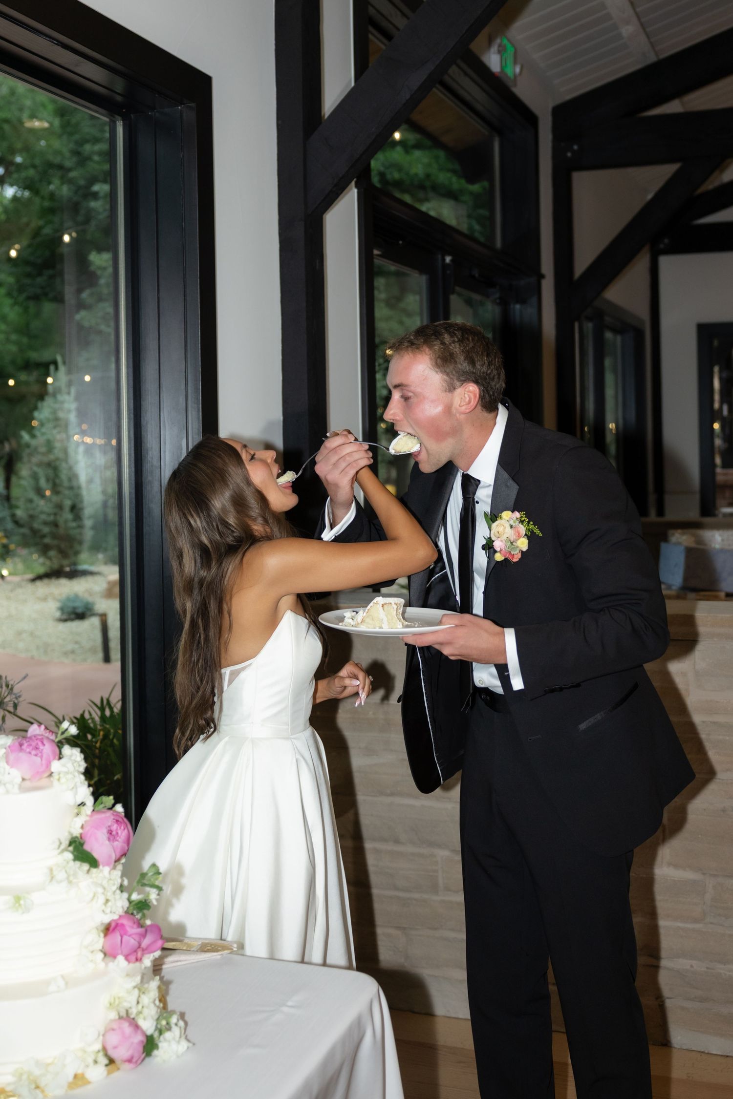 Newlyweds sharing cake in fun and playful moment during reception.