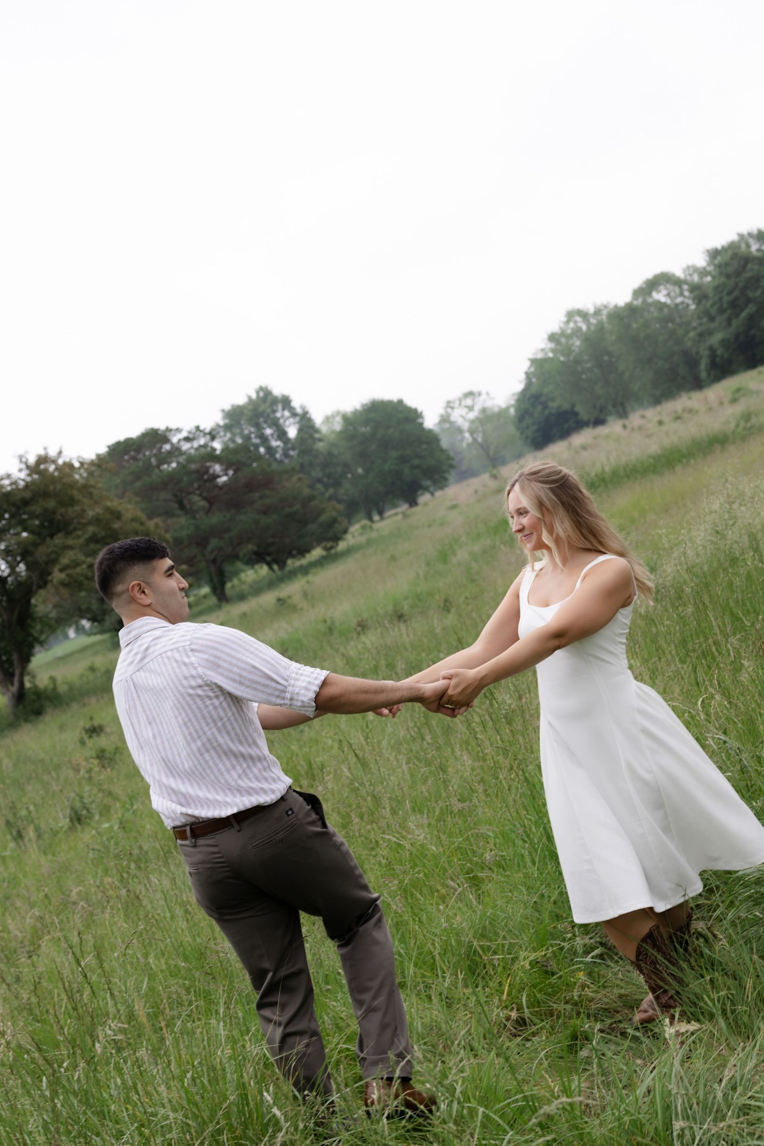Two people hold hands while spinning in a playful dance outdoors.