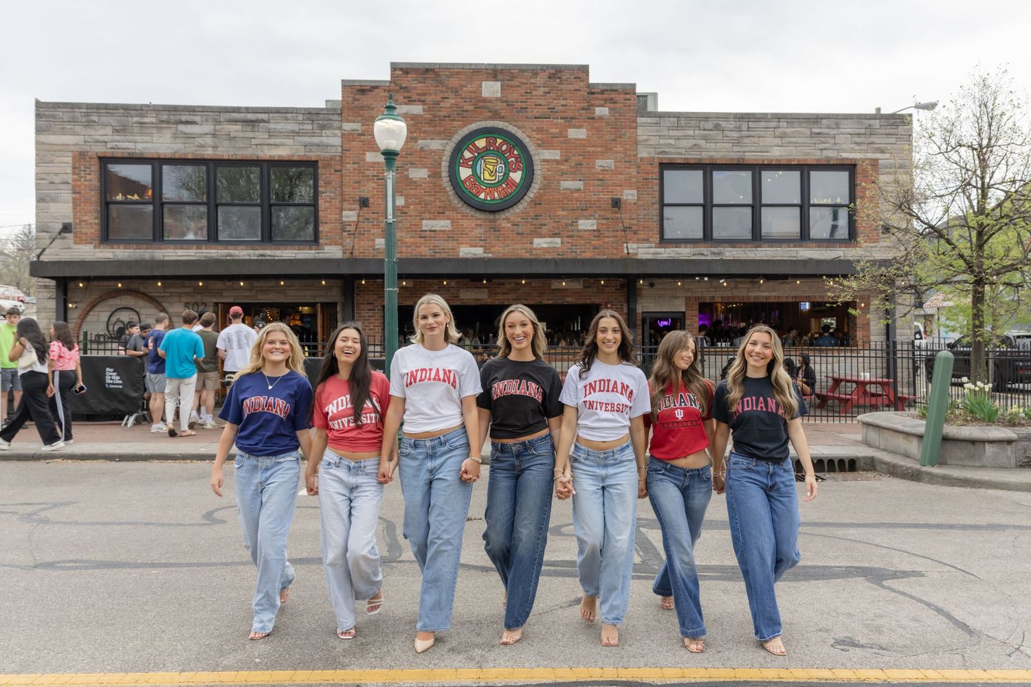 Students in matching outfits pose together in front of campus storefront.