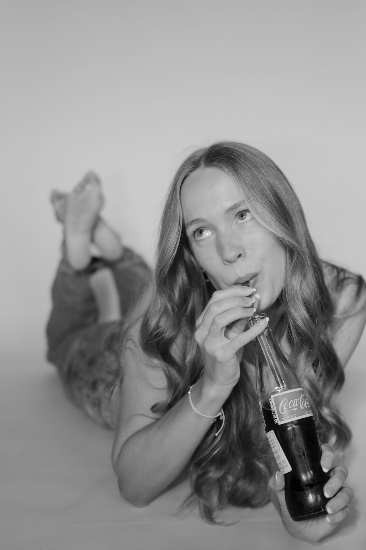 Playful black and white portraits with soda bottle against white backdrop.