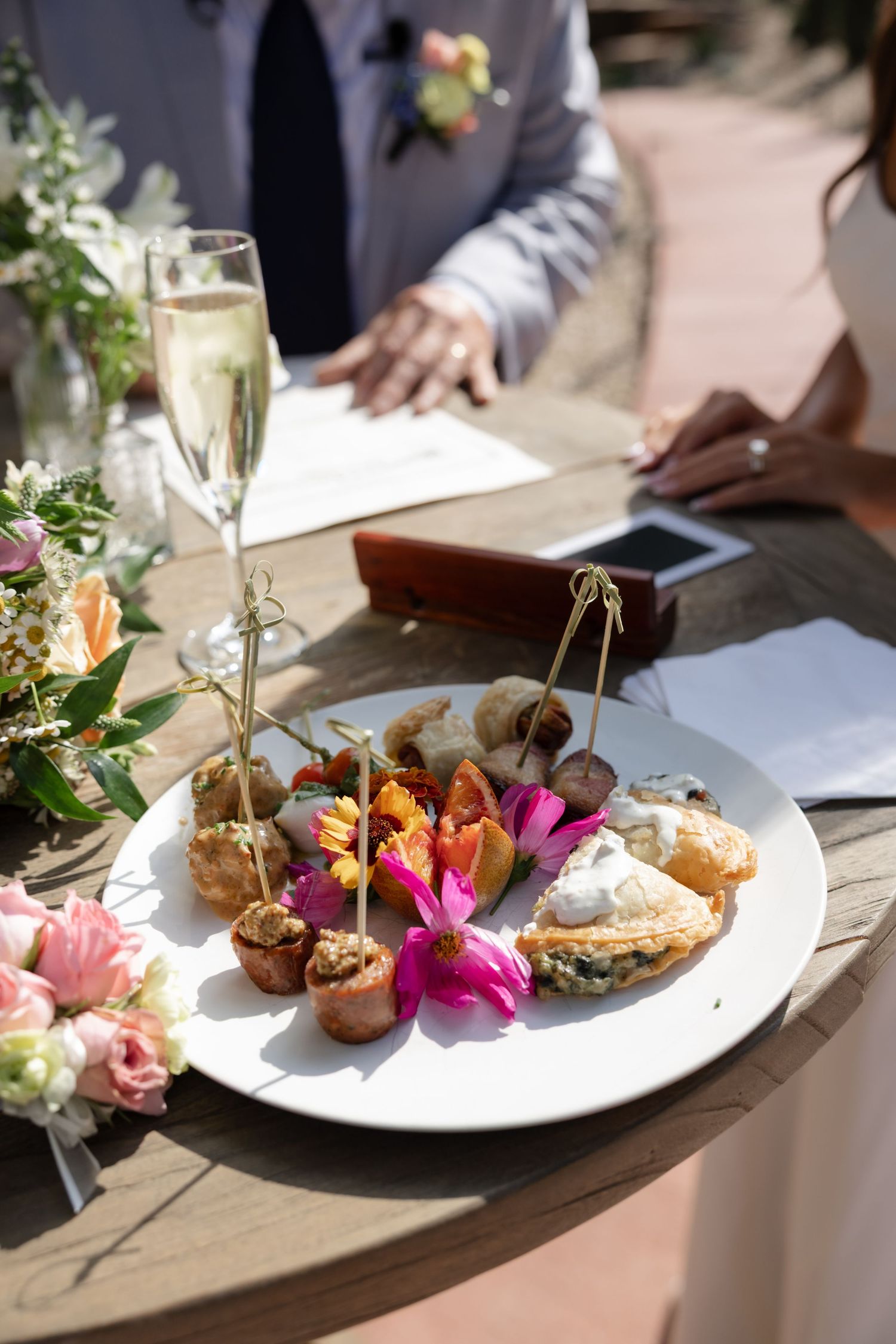 Gourmet appetizer plate with colorful flowers and champagne at an upscale event.