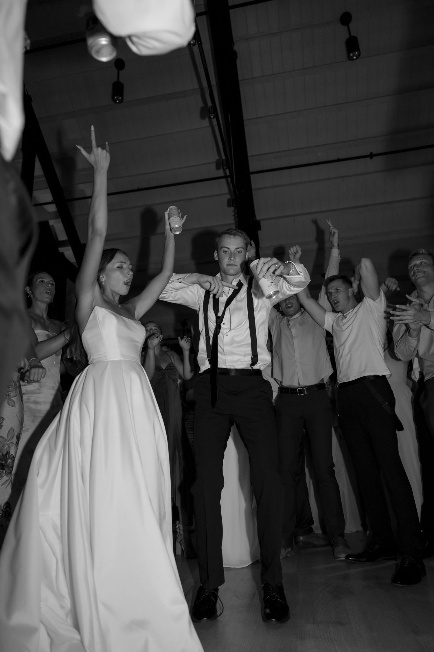 Black and white photo of wedding guests dancing at a reception.