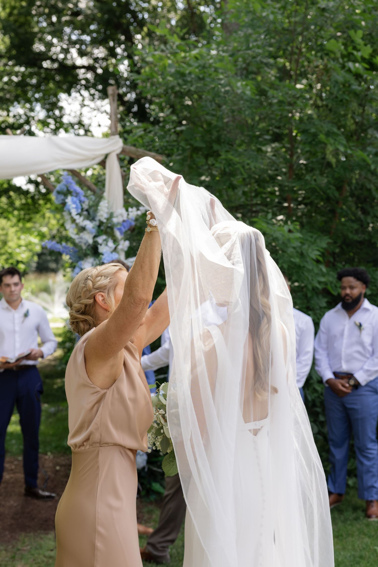 Wedding dress reveal moment in garden setting with attendants watching.