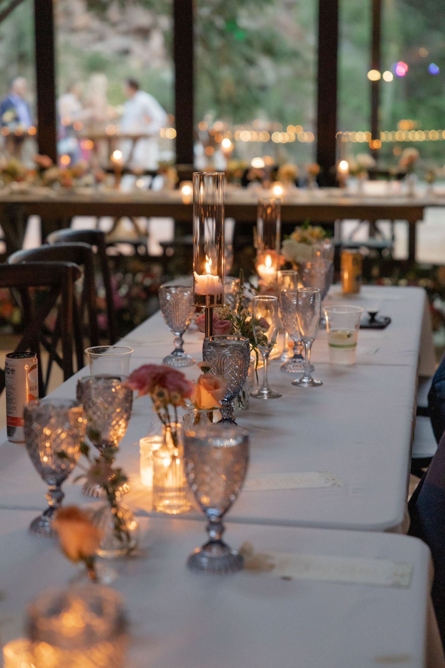Elegant wedding reception table set with white linens and glowing candles creating a romantic atmosphere.