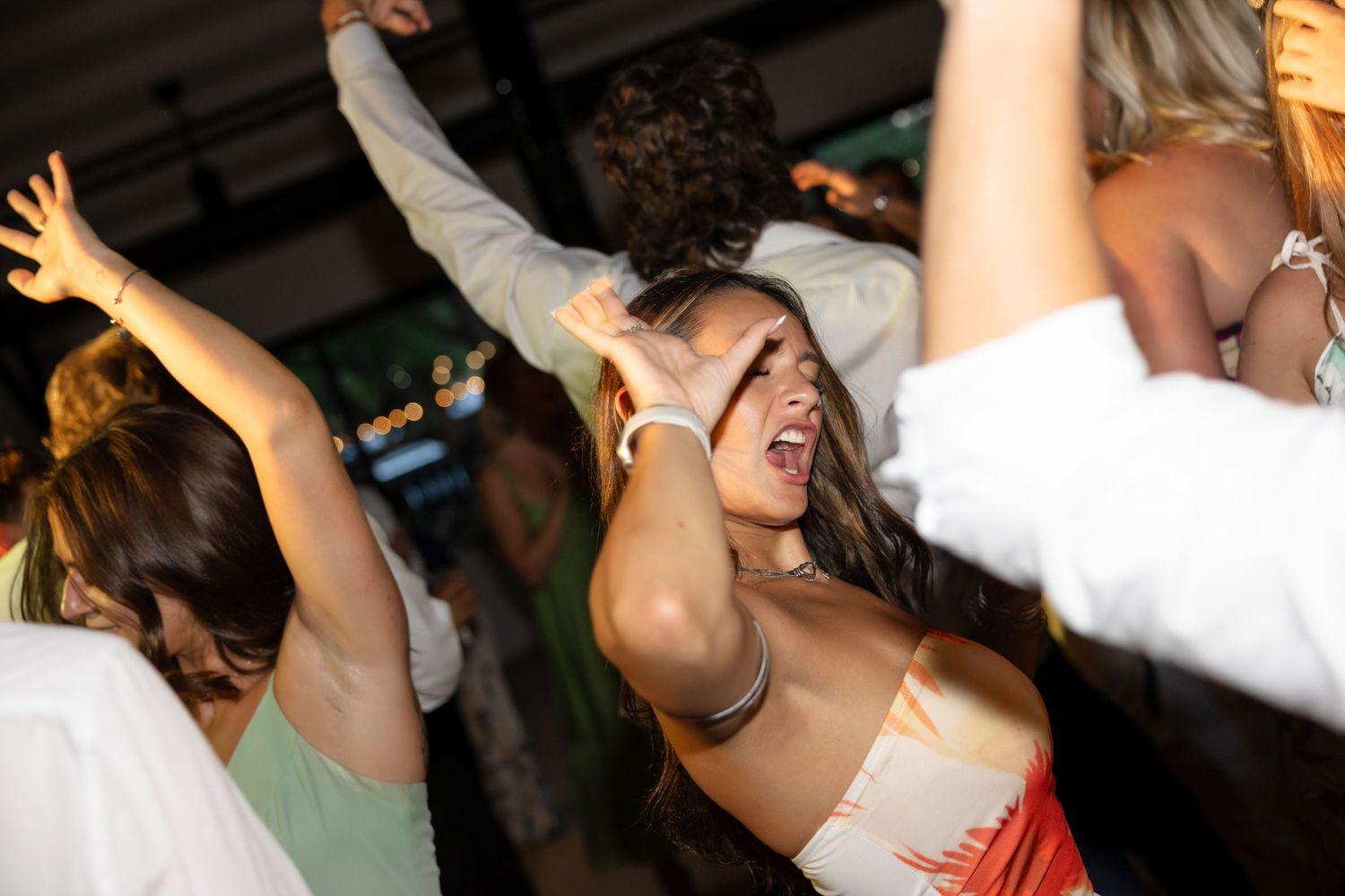 People raising their hands while dancing at a wedding celebration.