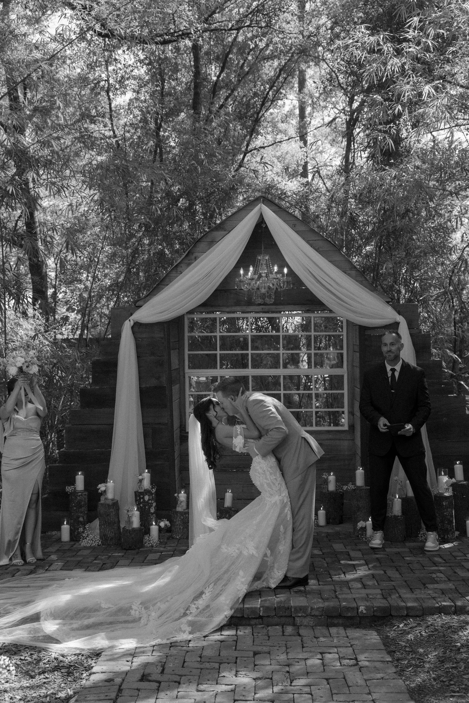 Wedding photos in front of a draped outdoor pavilion with a long flowing bridal dress trailing on brick pavers.