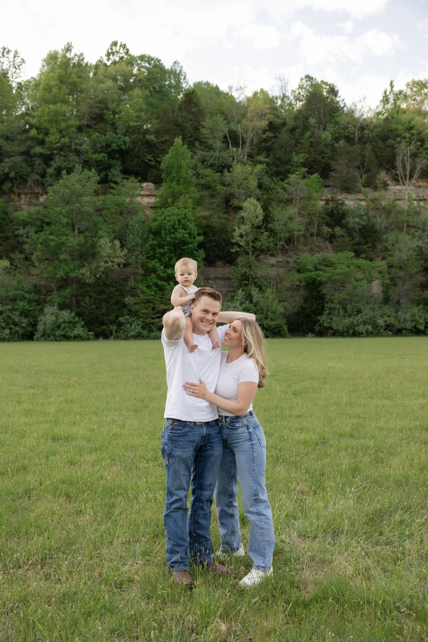 Family stands together in an open field sharing loving moments.