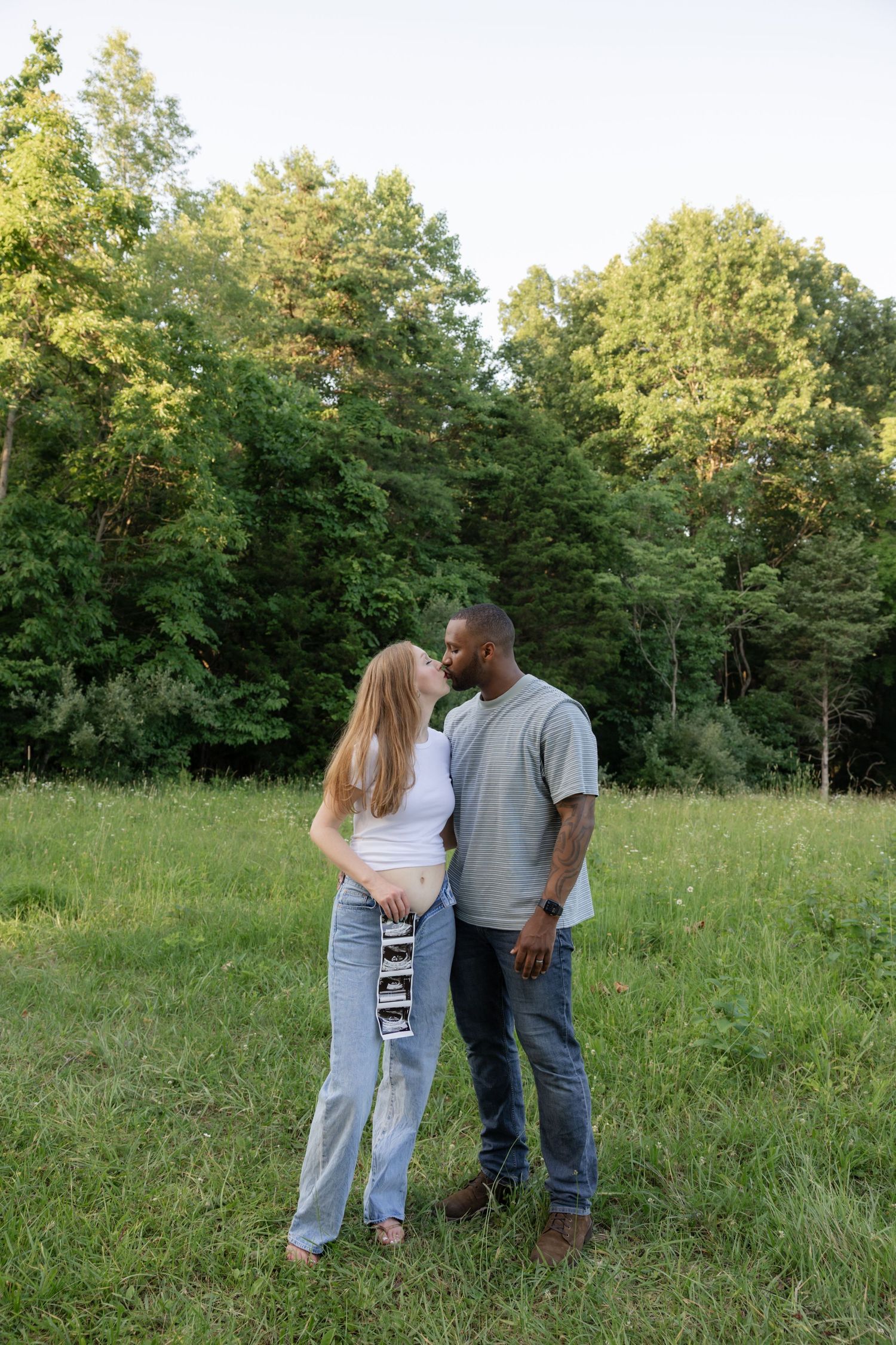 Family sharing intimate moments in a sun-lit meadow.