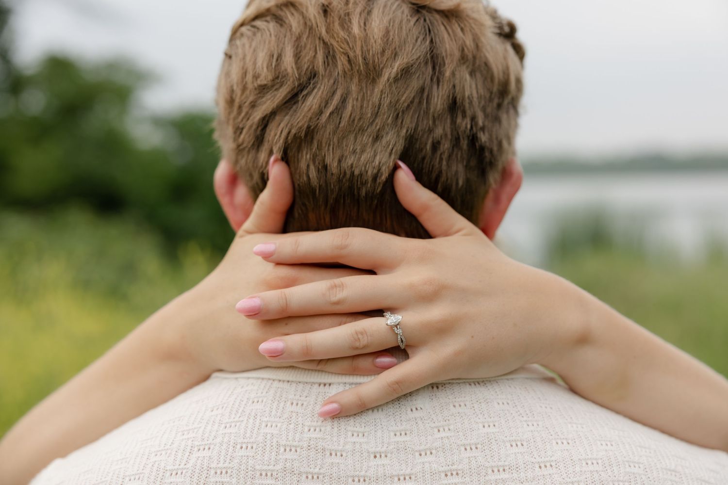 Close-up shot focusing on hands tenderly embracing a neck against a light background.