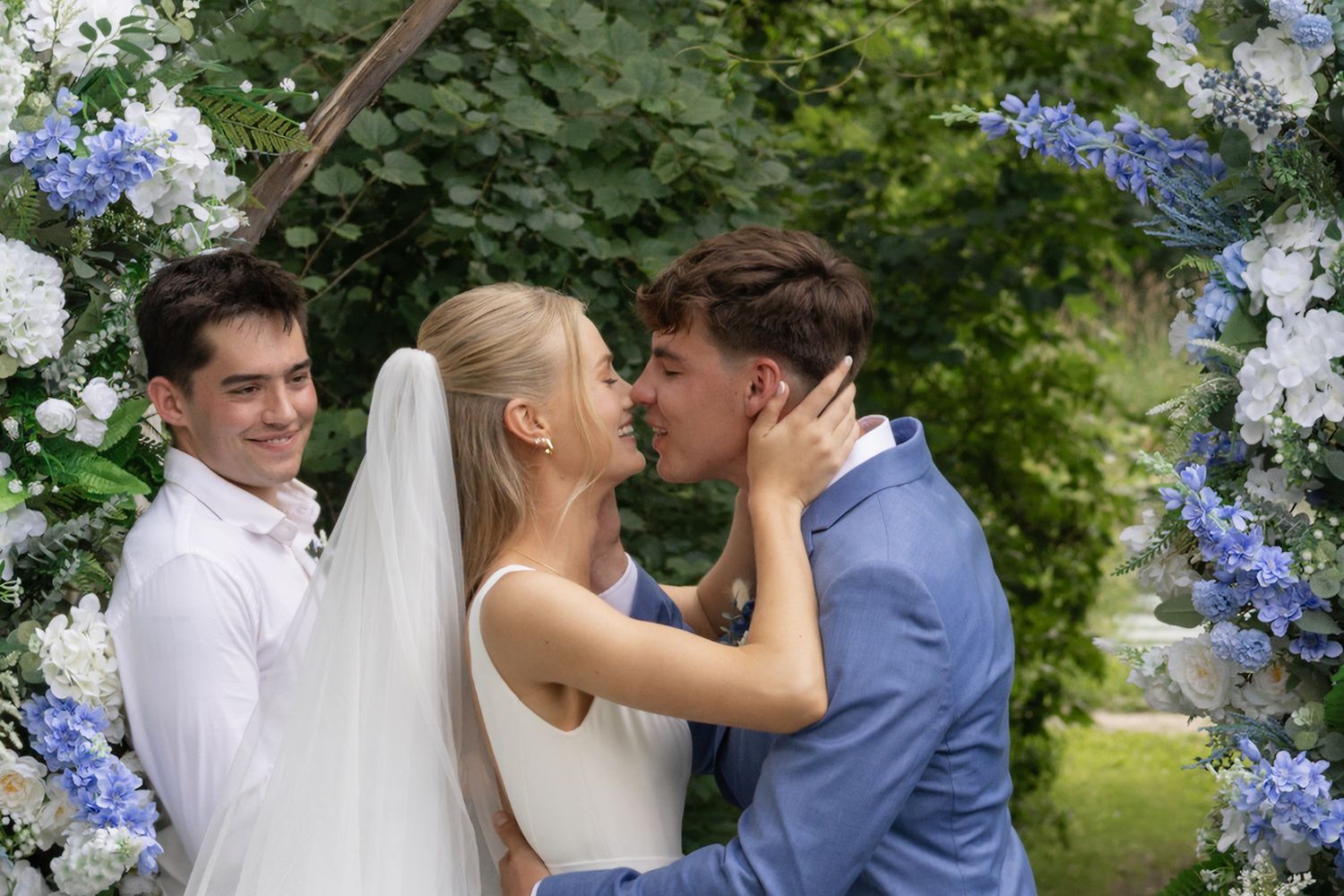 Intimate garden wedding ceremony with blue hydrangeas and white drapery decorations.