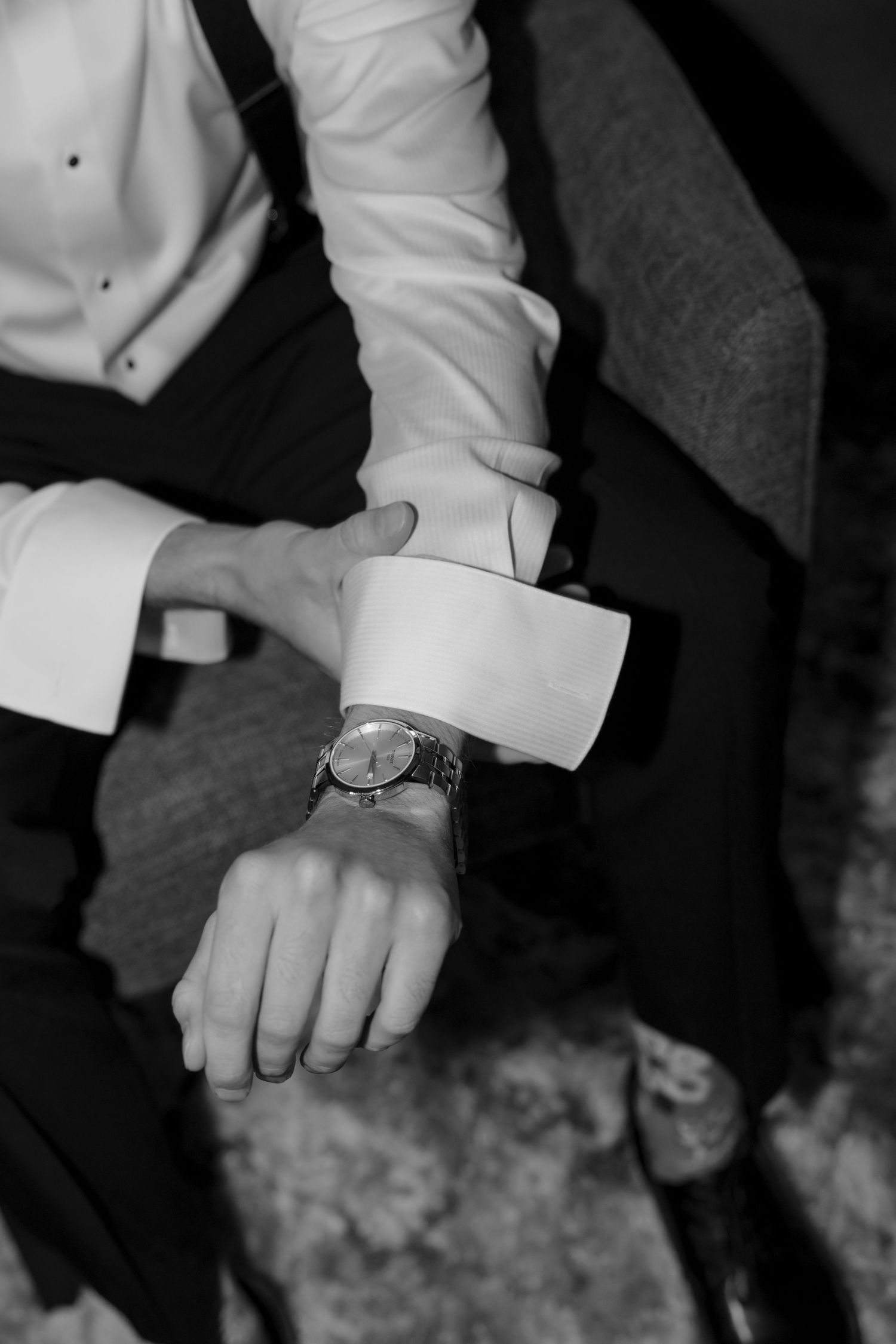 Black and white close-up of hands holding during an intimate wedding moment.