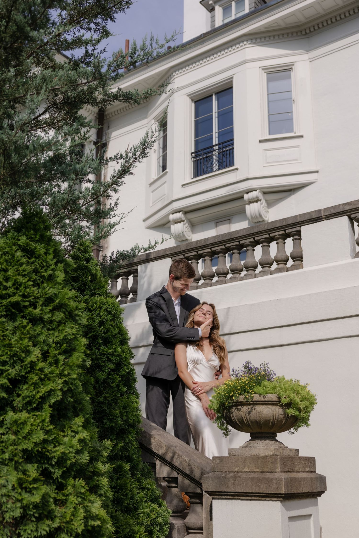 Romantic scene against white mansion wall with decorative stone balustrade and garden urn.