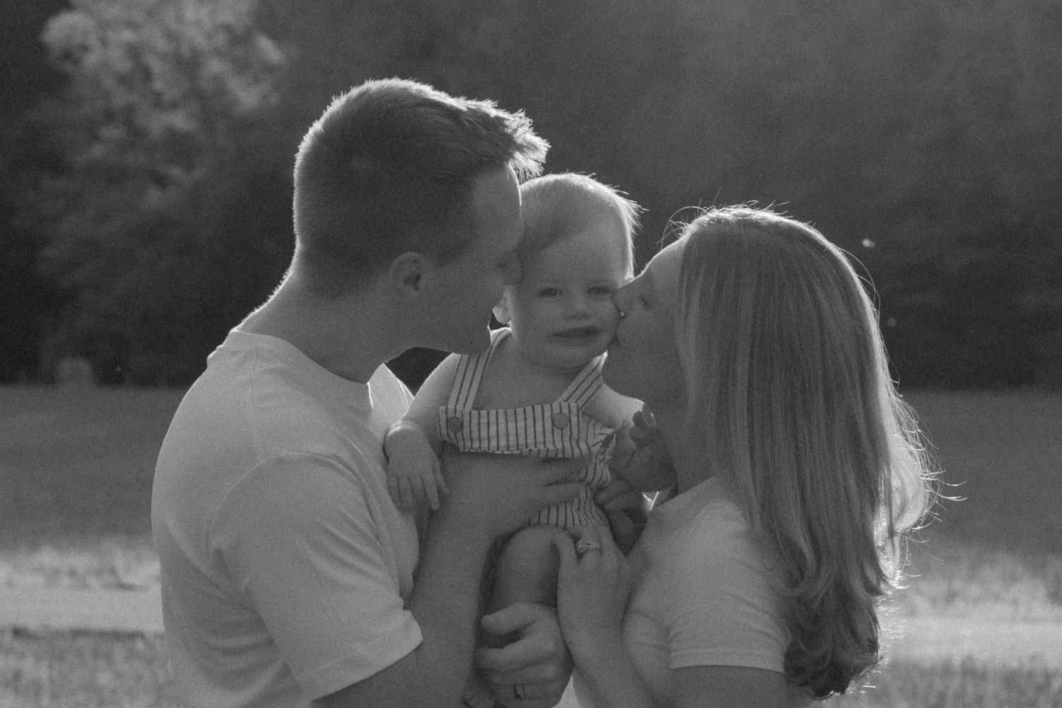 A black and white family portrait sequence showing tender moments outdoors.