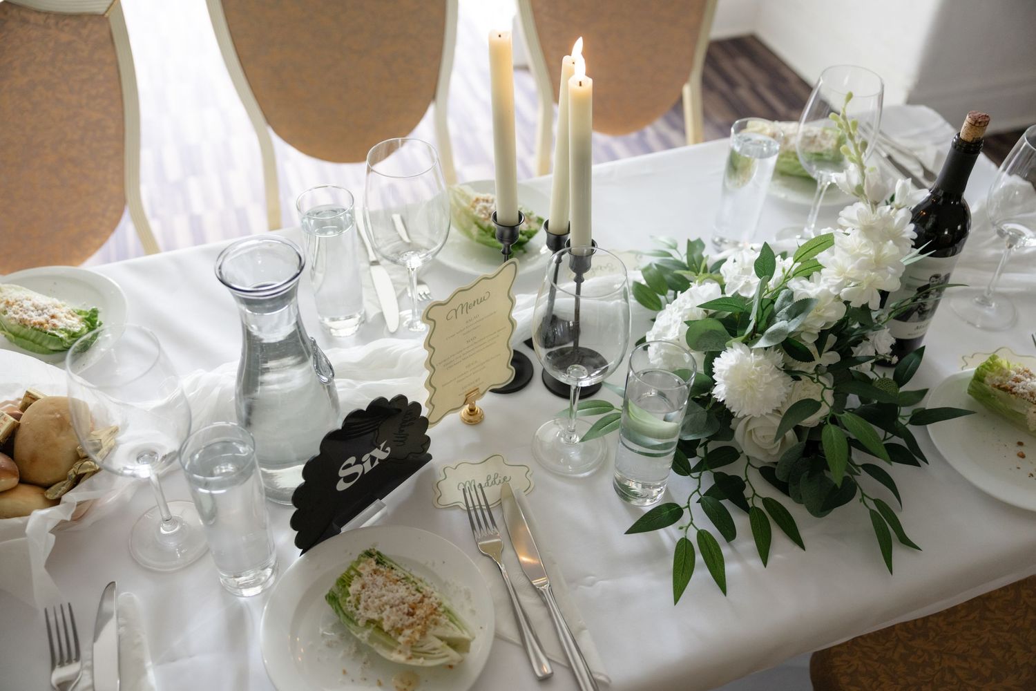Elegant wedding reception table decorated with white floral arrangements and crystal glassware.