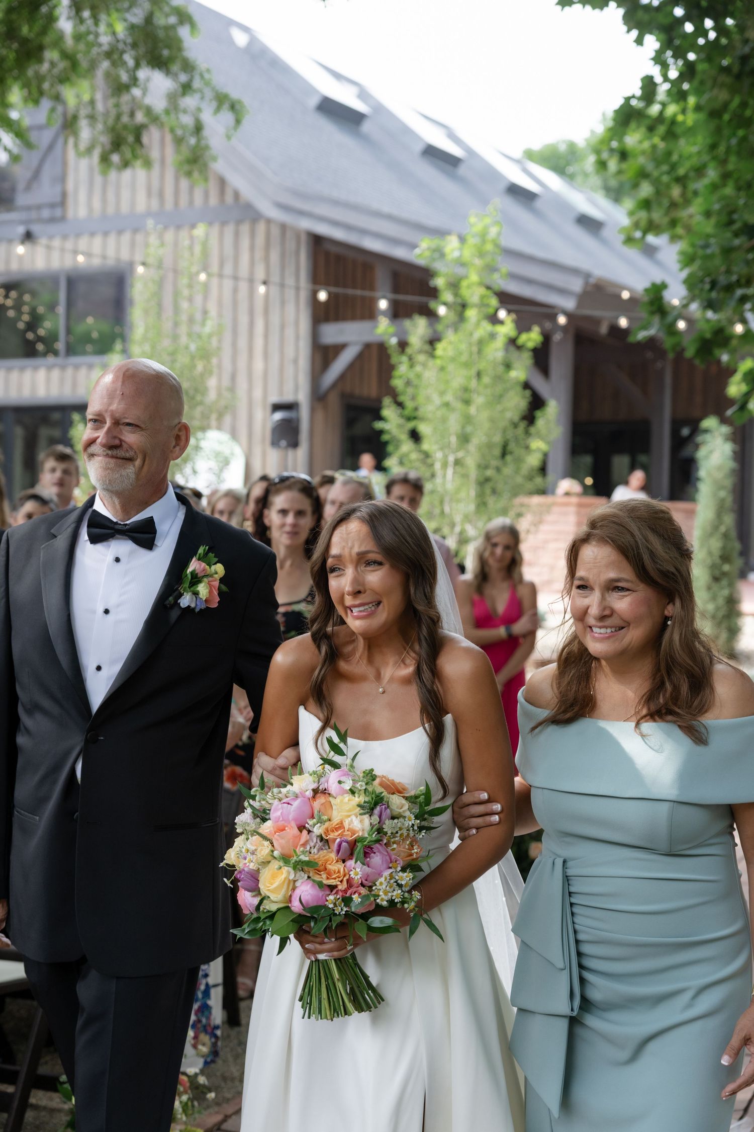 Wedding party walking and laughing together outside rustic barn venue.