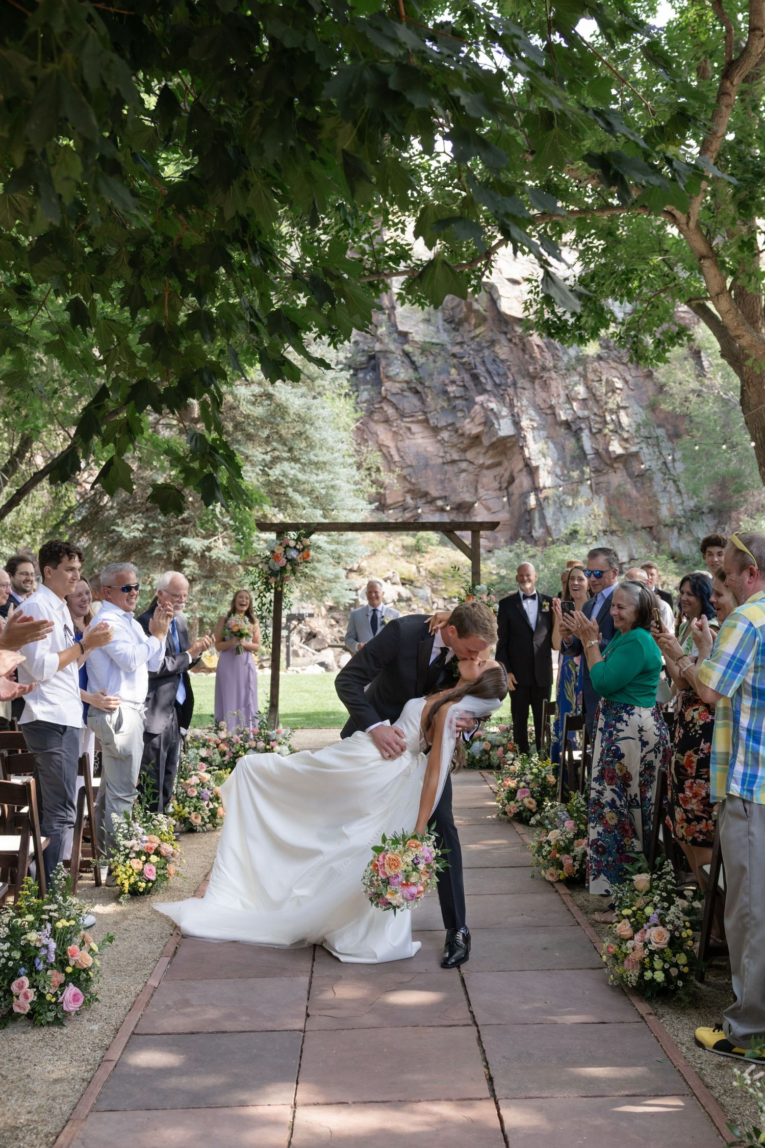 A romantic dip pose during a wedding ceremony as guests capture the moment on their phones.