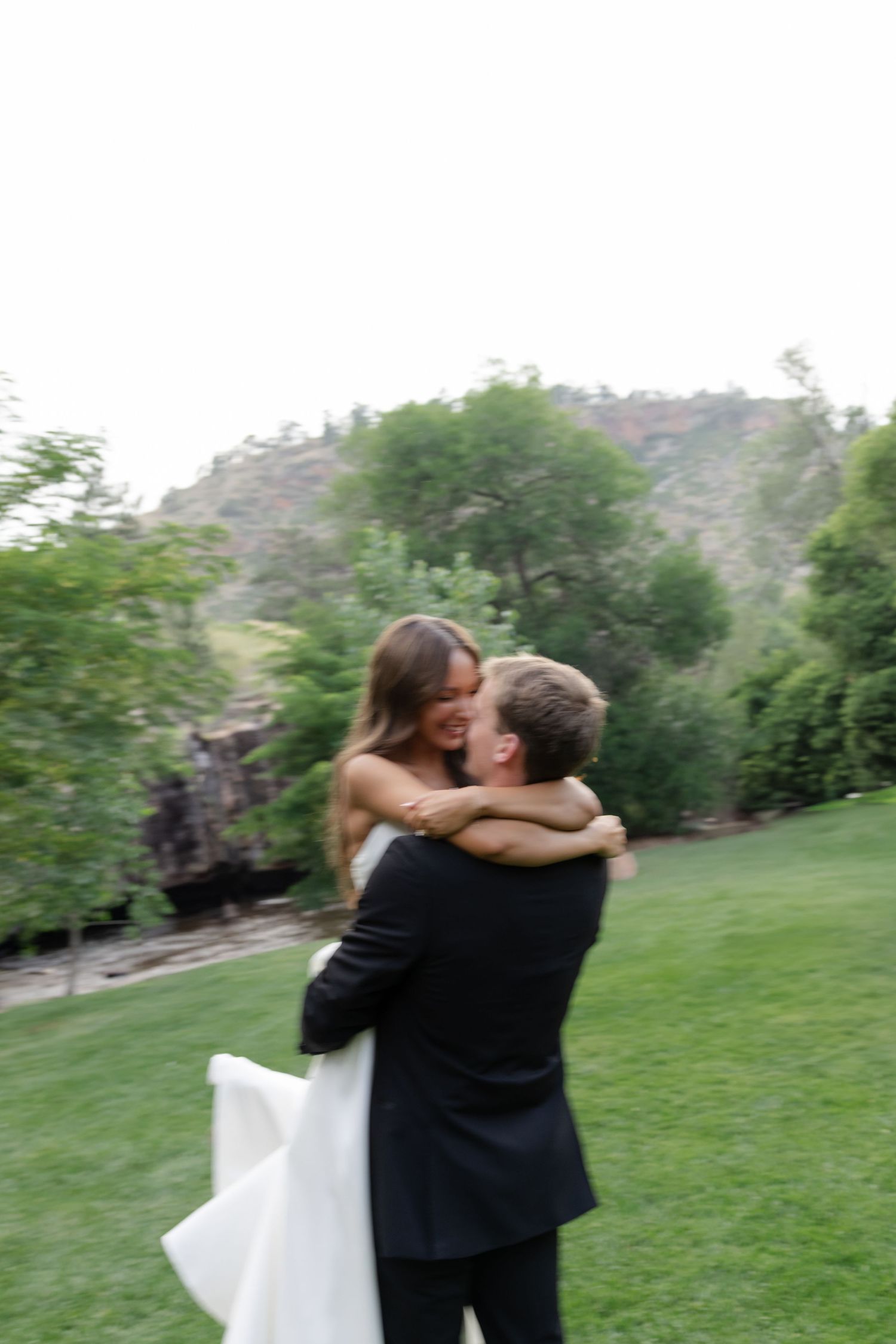 A romantic moment captured in motion as newlyweds embrace on their wedding day in a garden setting.