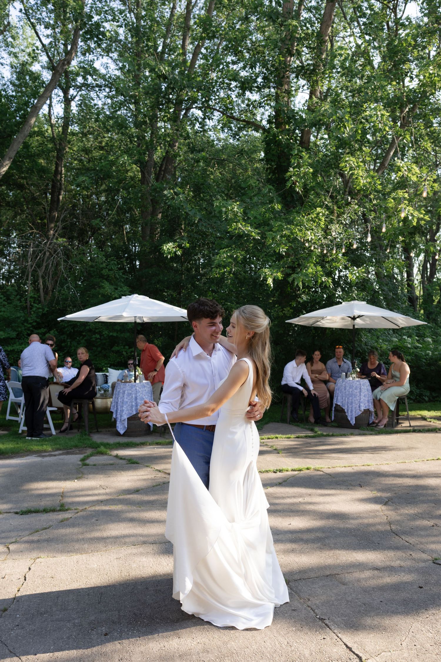 A couple dancing outdoors under white tents during their wedding celebration.