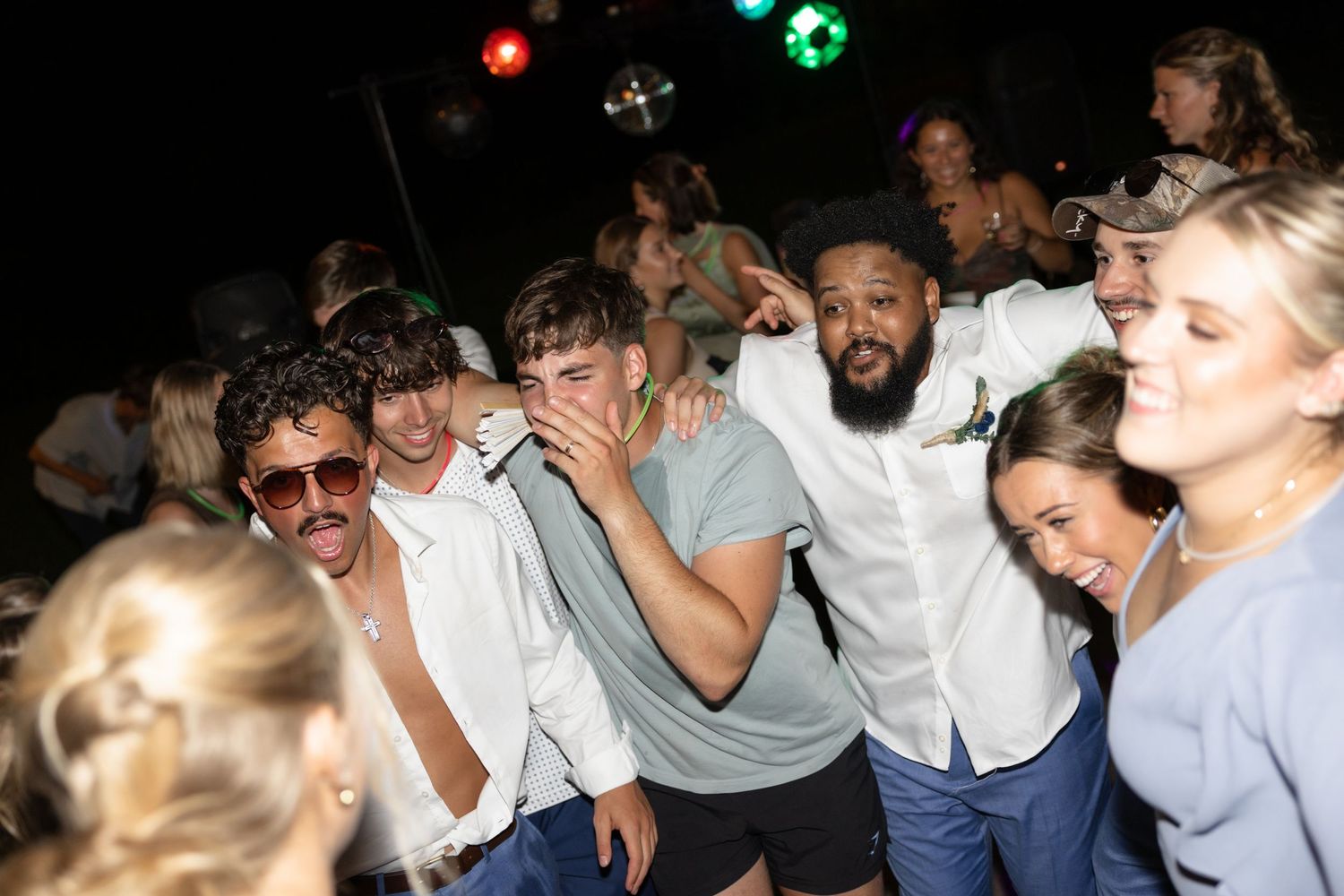 A group of party guests dance and celebrate together at a nighttime celebration.