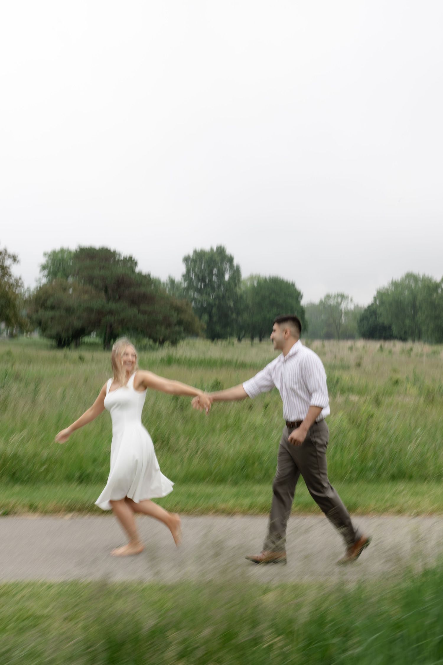 A couple dances and spins playfully together in a green summer meadow.