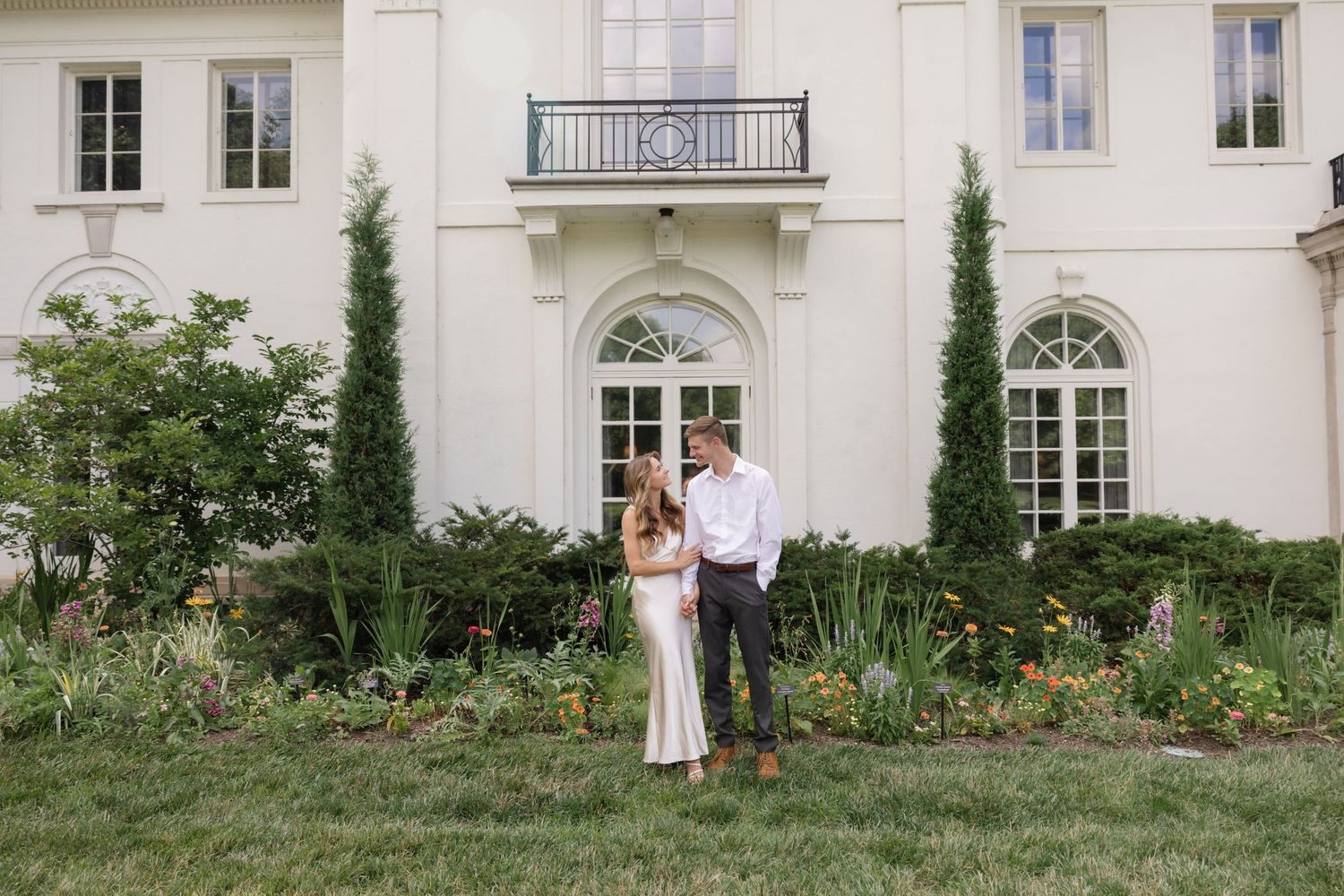 A white mansion with classic architecture serves as backdrop for a romantic photoshoot.