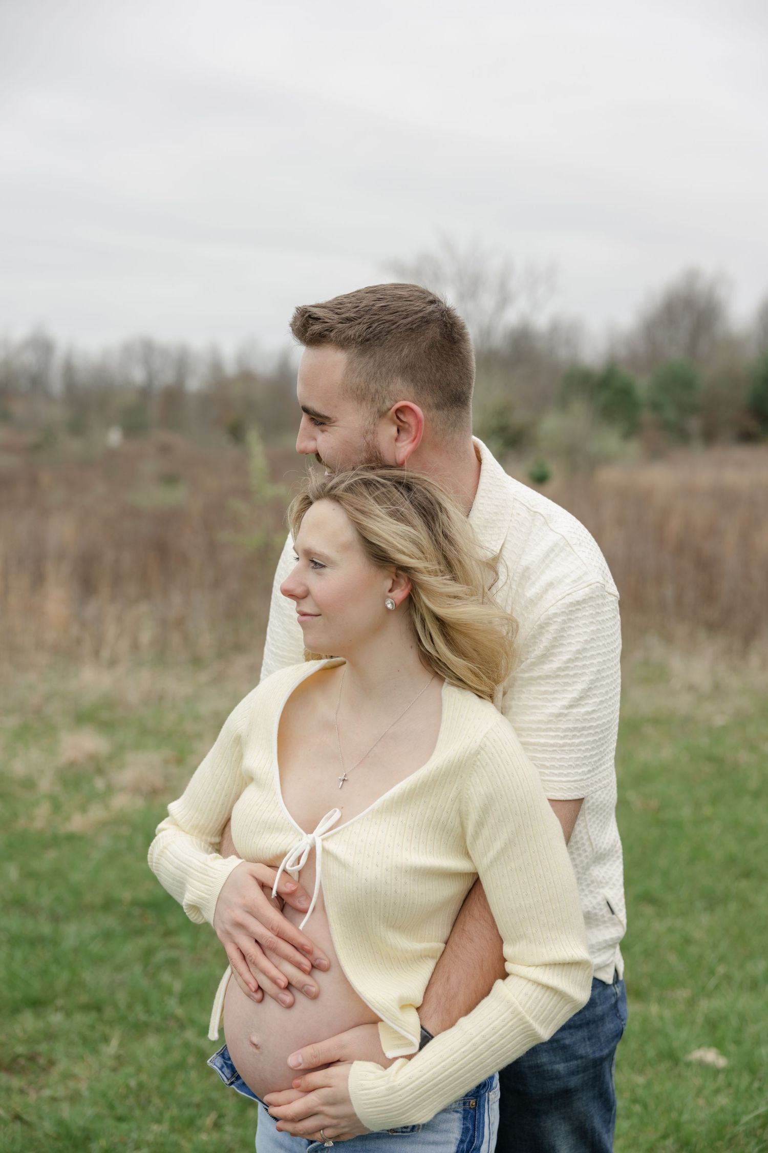 A romantic maternity photoshoot featuring a couple embracing in a spring field.