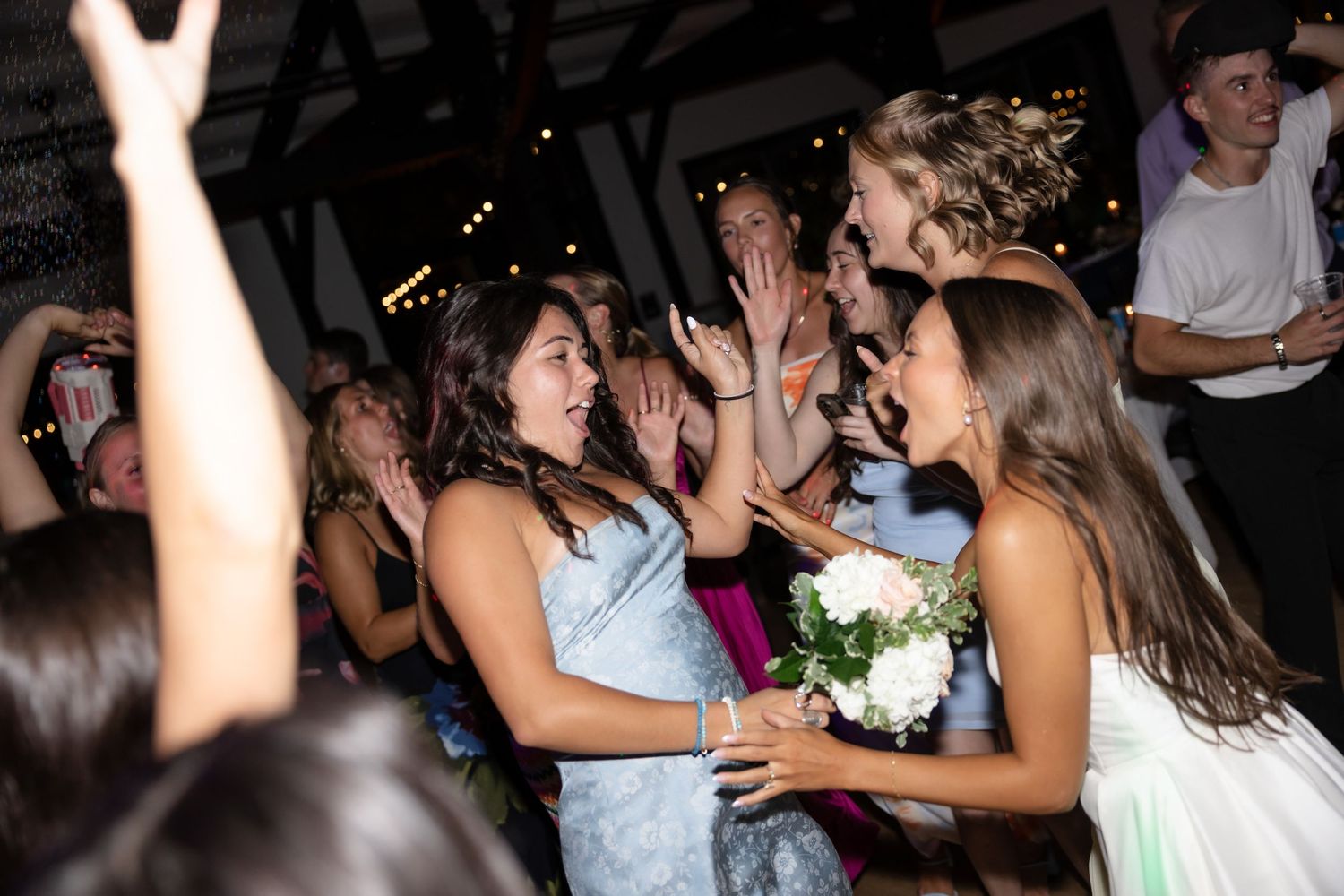 Energetic dancing and celebration at a dimly lit wedding reception.