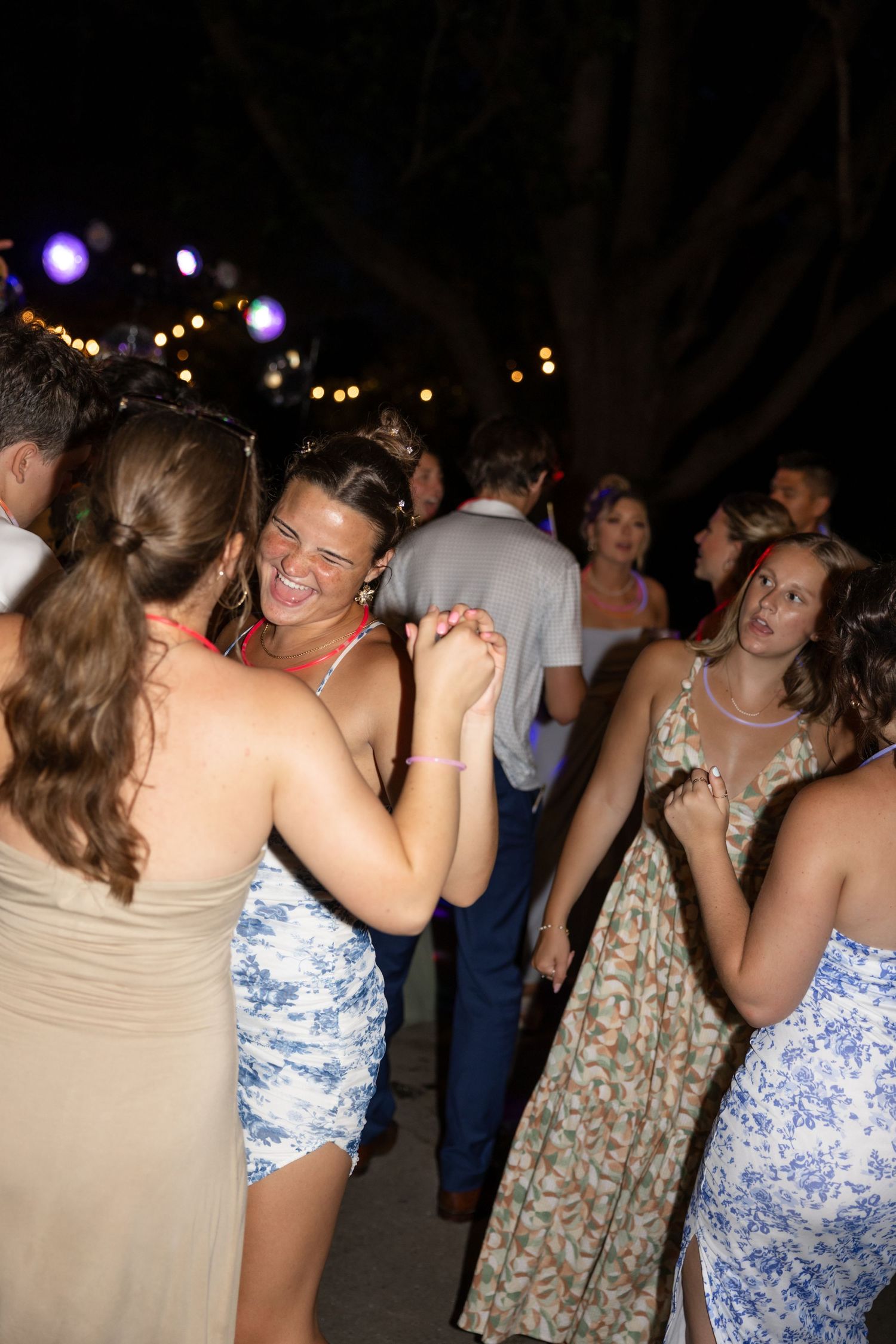 People dancing and socializing at a lively outdoor party with ambient lighting.