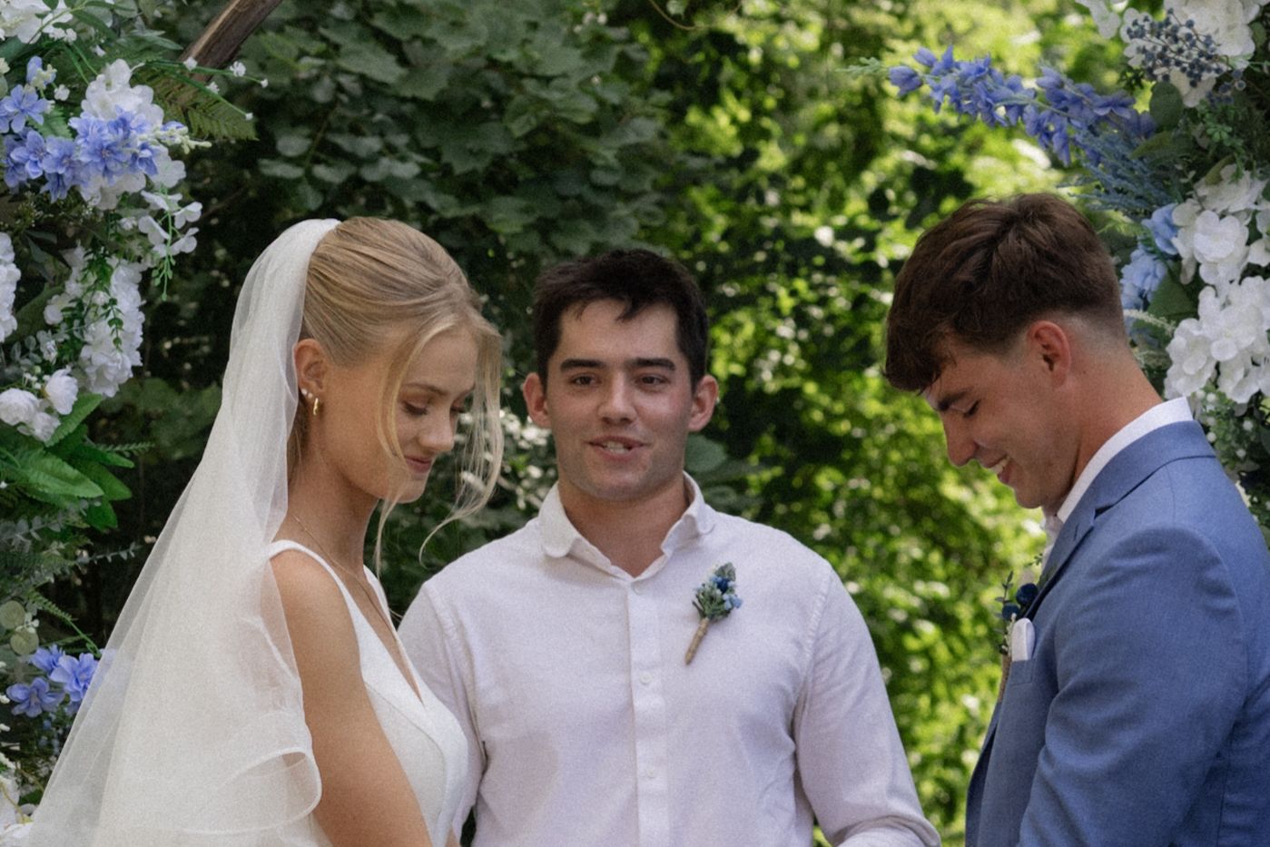 Candid moments from an outdoor wedding ceremony with white and blue floral decorations.