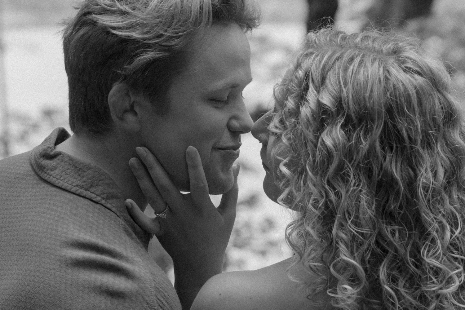 Black and white portrait of a couple in an intimate moment outdoors.