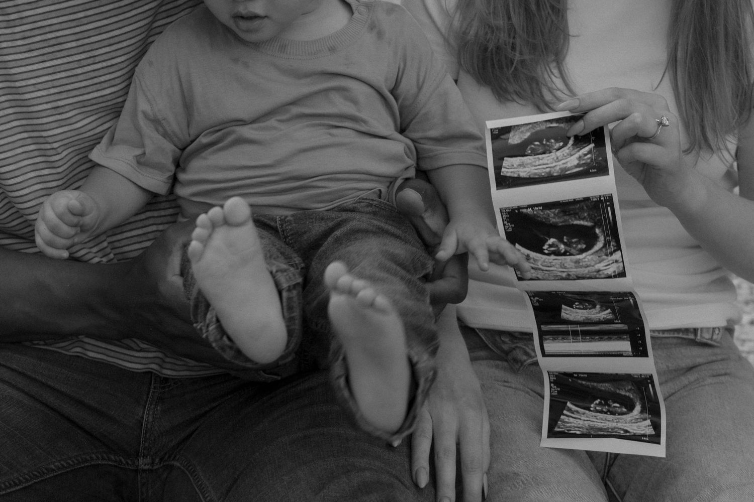 Close-up of hands holding and reviewing ultrasound photos during a pregnancy announcement.