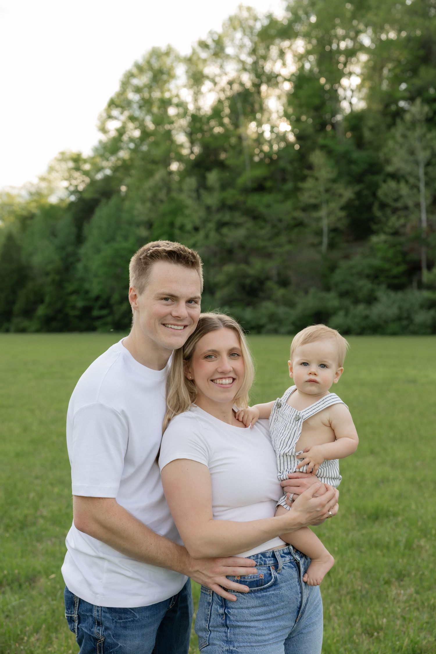 Joyful family moment captured outdoors in a grassy field at sunset.