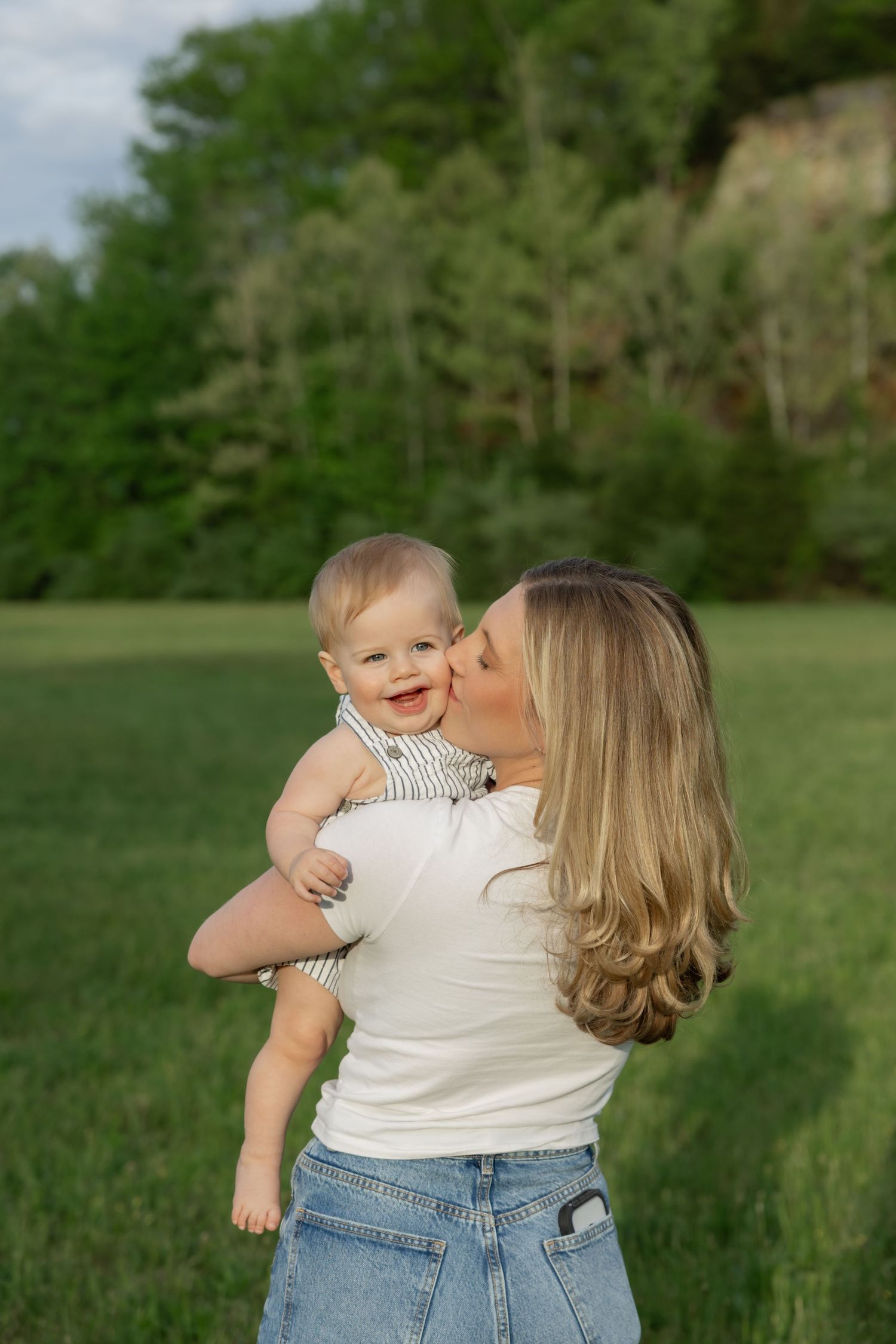 Mother and baby share loving moments in a sun-drenched green field.