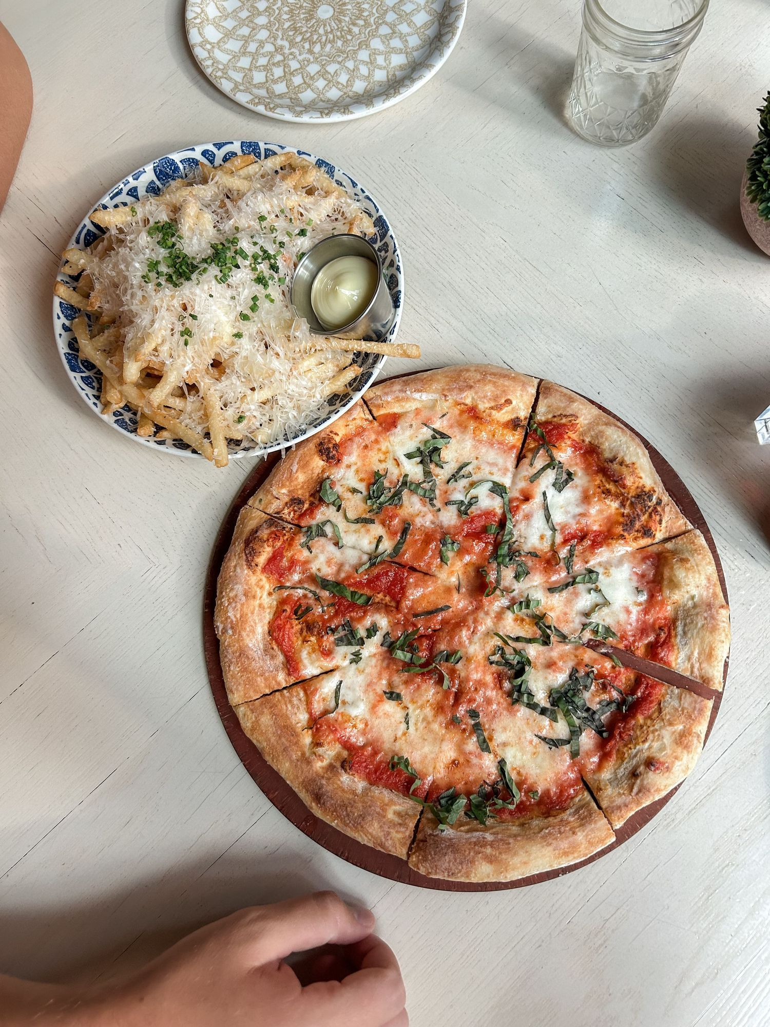 Fresh pizza with melted cheese and herbs served on a wooden board with garnishes.