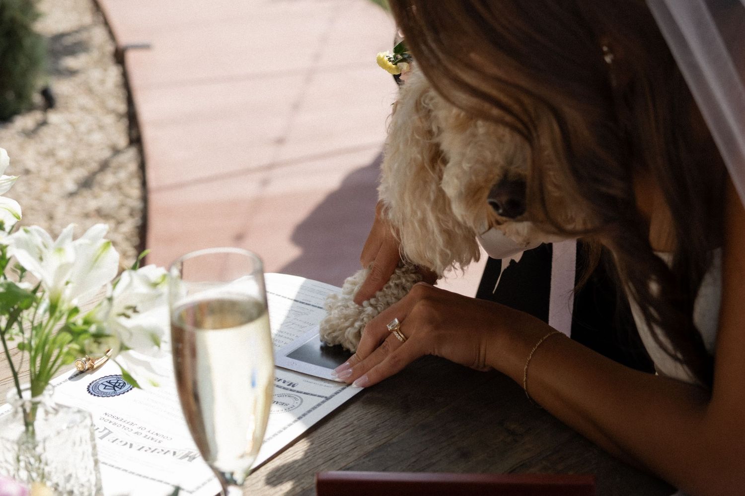 A close-up of wedding document signing with champagne and floral decorations on the table.