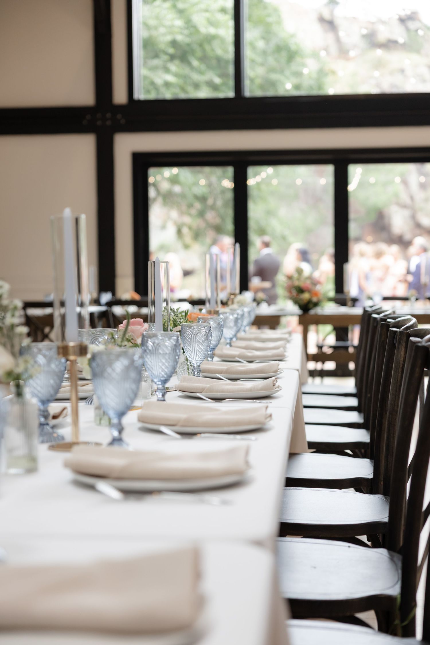 Formal dining room setup with white tablecloths and place settings in a light-filled space.